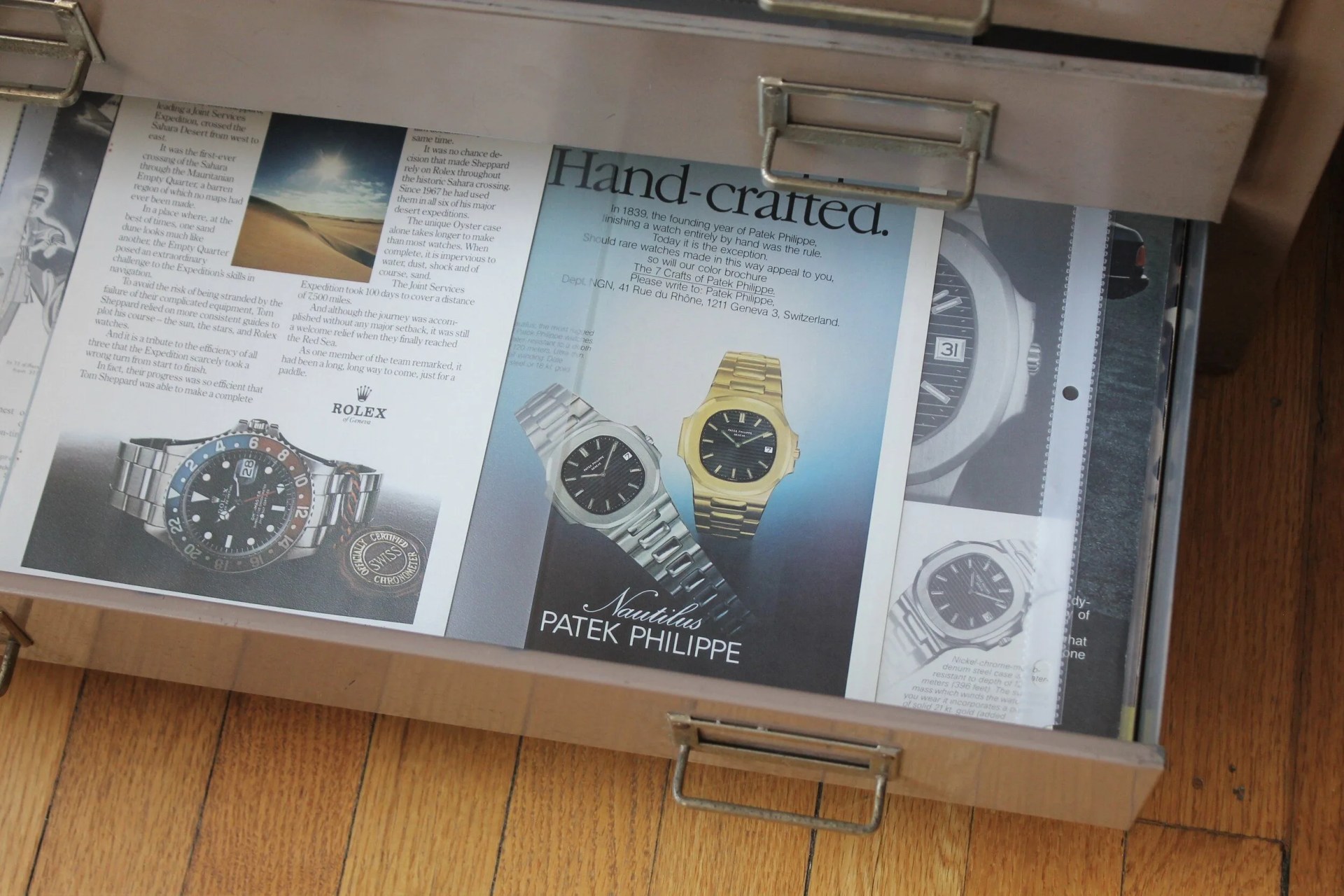 a metal drawer full of old print watch advertisements