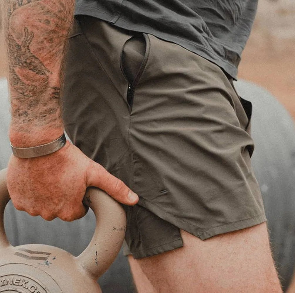 a man wearing olive shorts carrying a weight