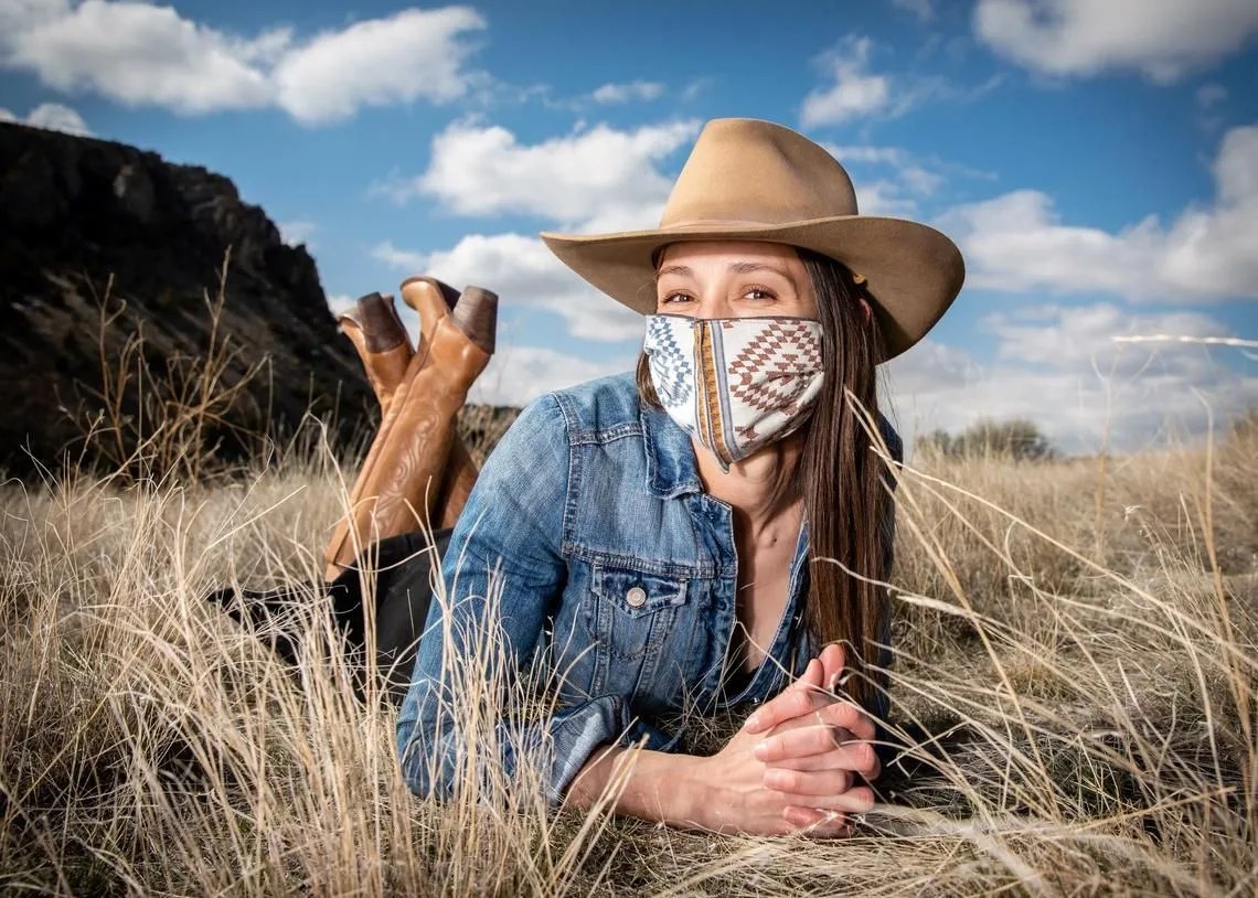 person wearing western hat face mask denim jacket and boots