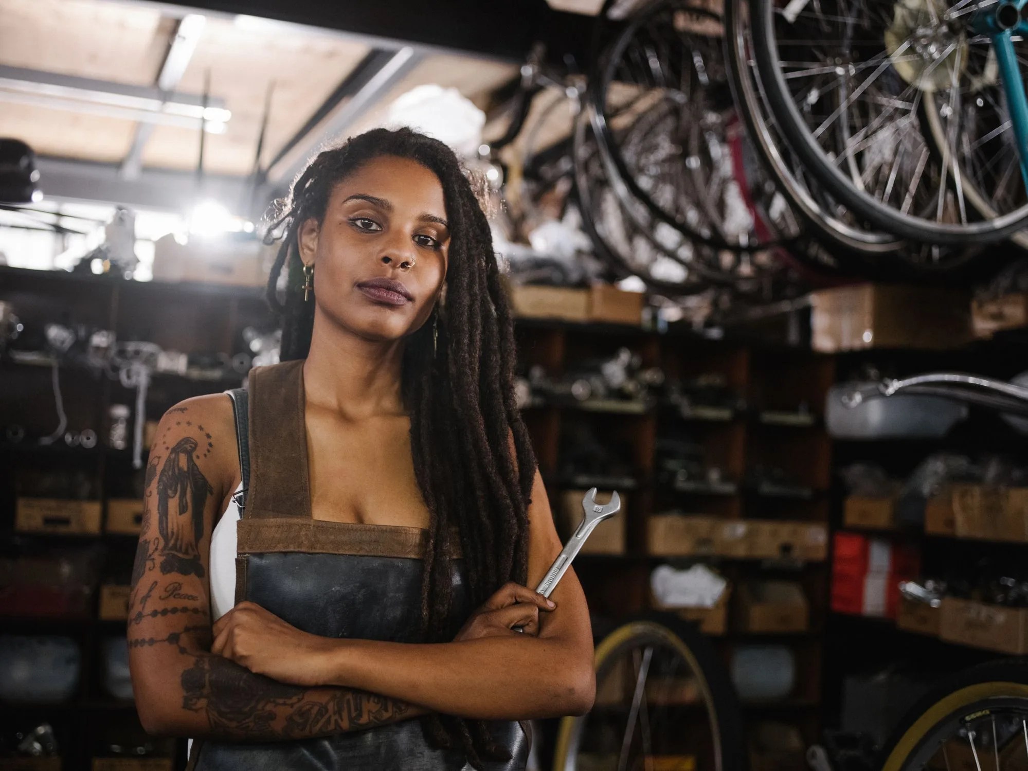afro woman bicycle mechanic looking proud in bike repair worksho