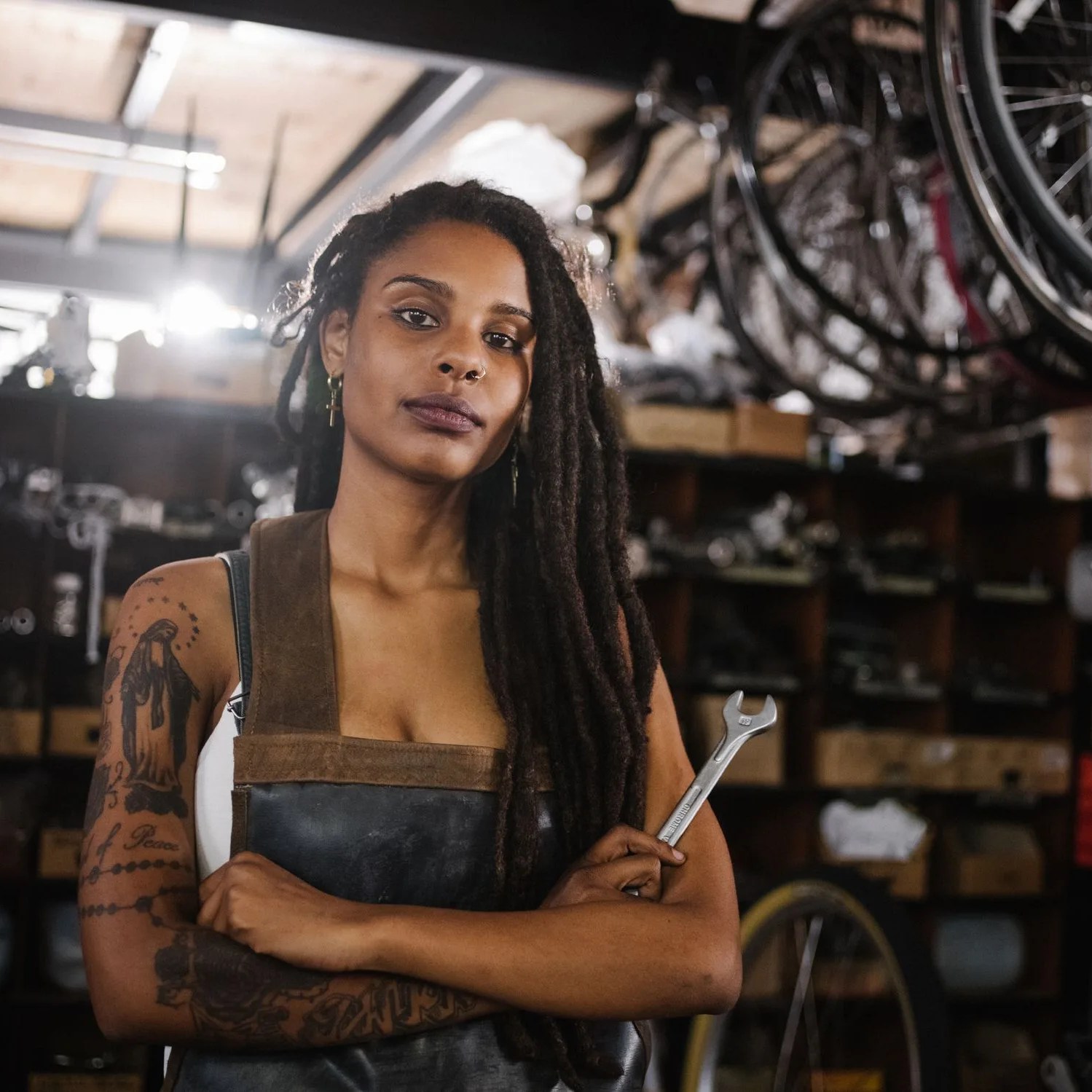 afro woman bicycle mechanic looking proud in bike repair worksho