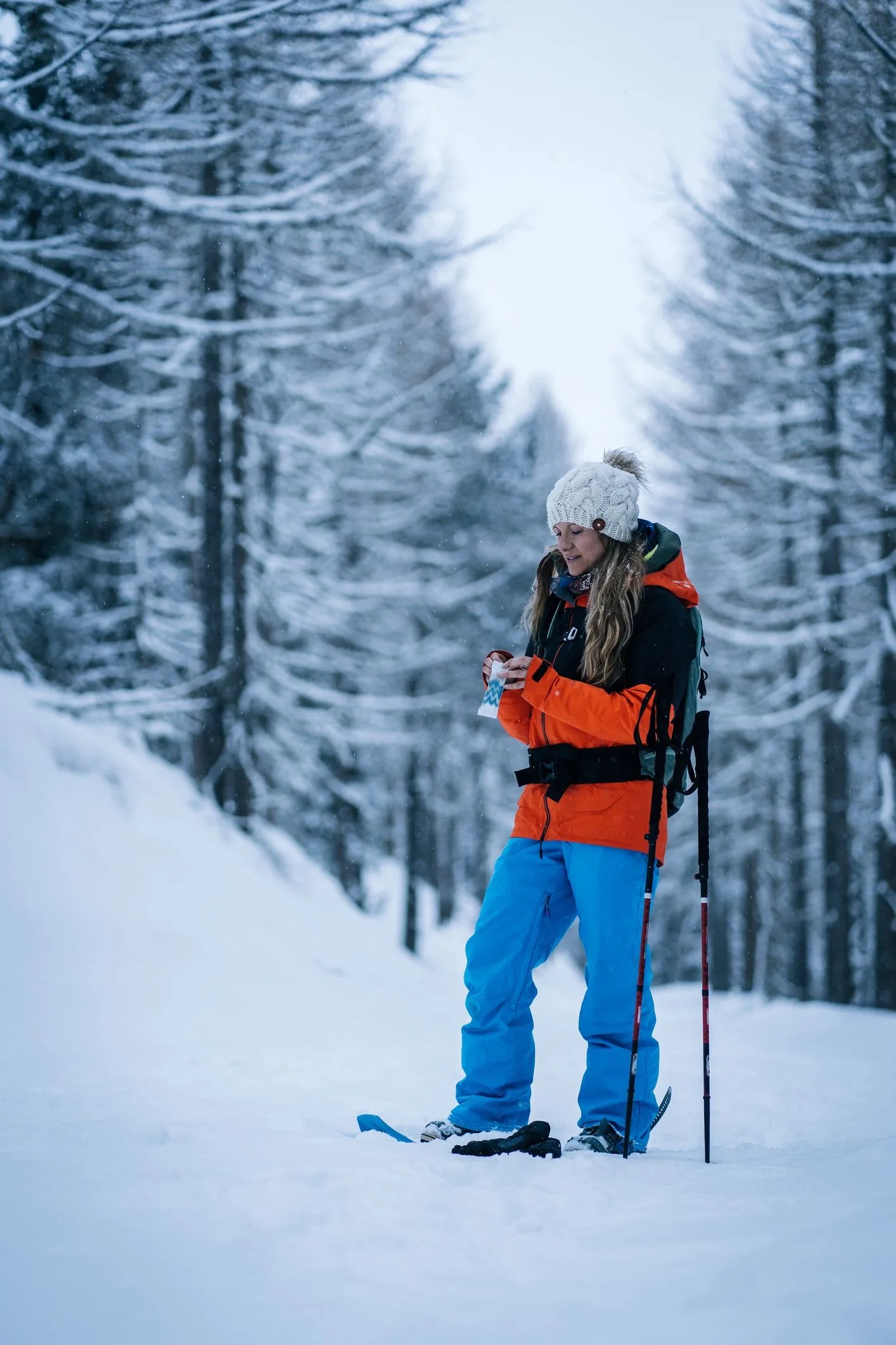 female snowshoer enjoys snack in snowy forest