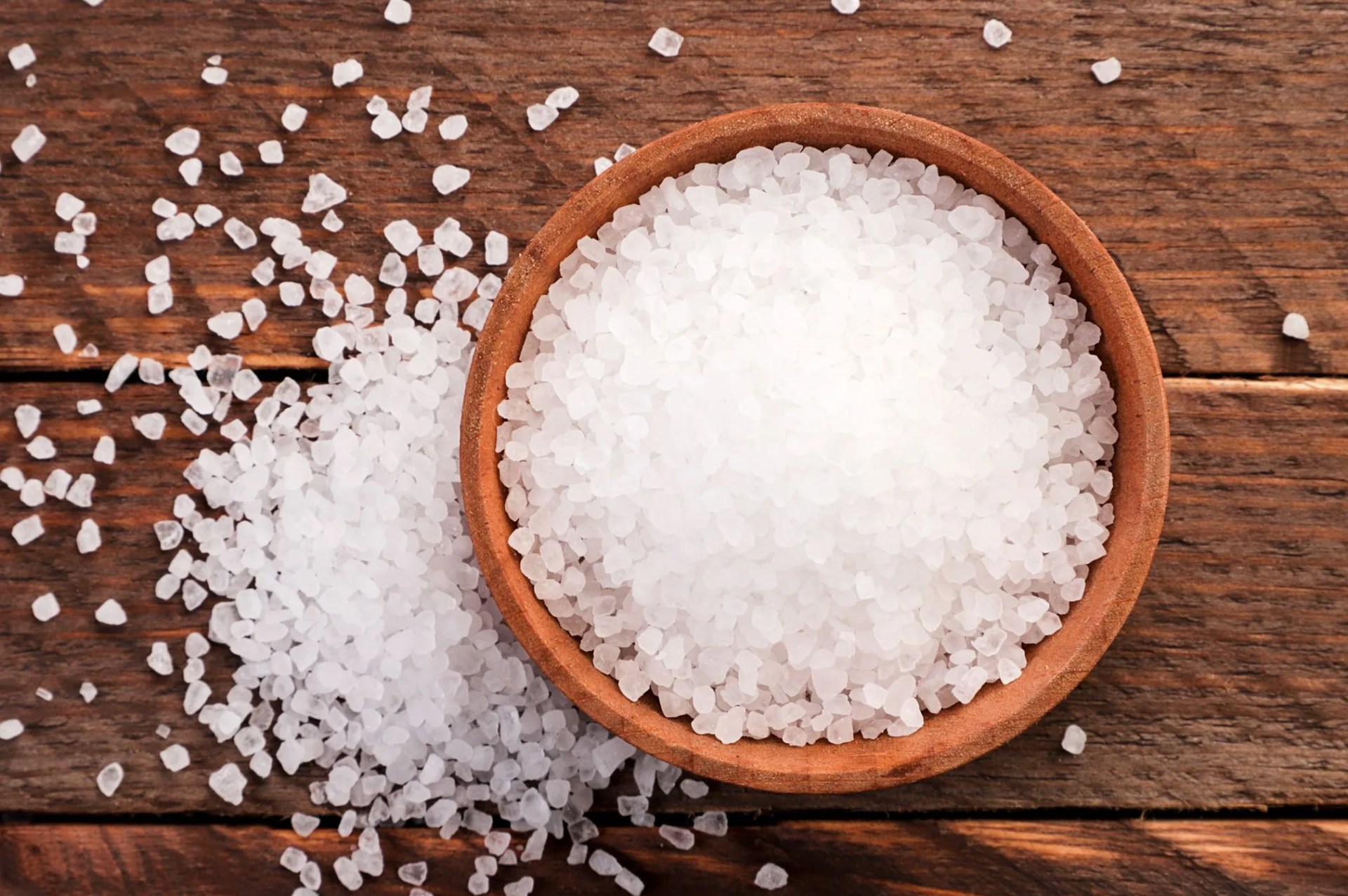 salt in a plate and sprinkled on a wooden background the view from top