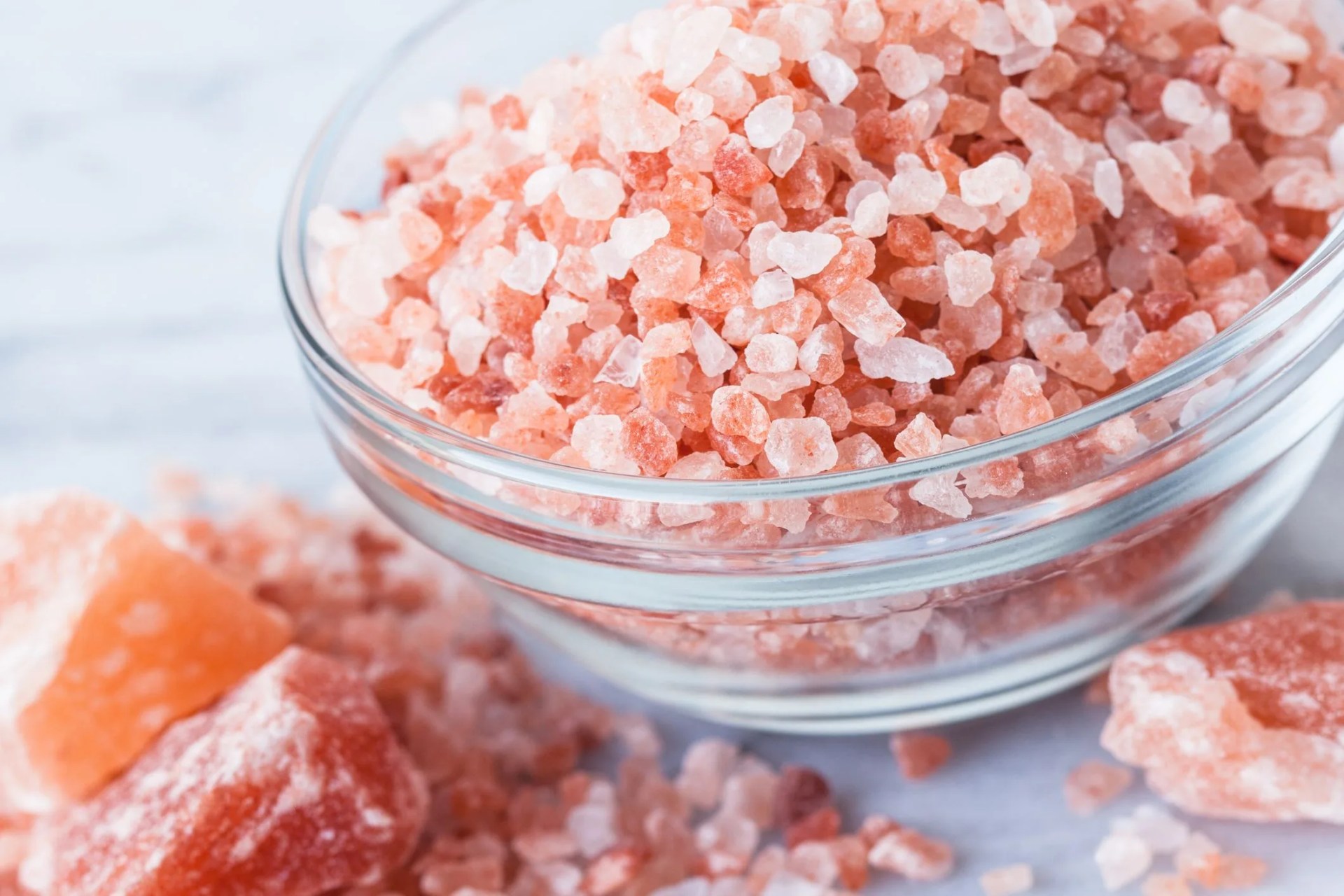 natural light photo of bowl of himalayan pink salt in with small and large chunks selective focus on top of salt in bowl