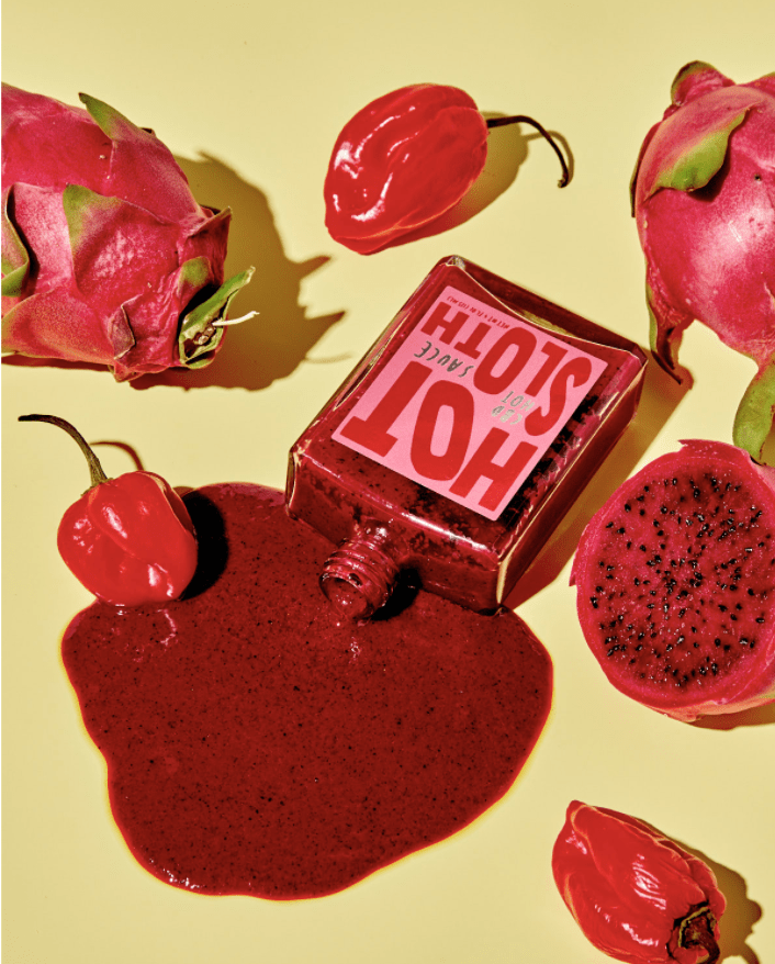 spilled red hot sauce surrounded by dragon fruit and peppers