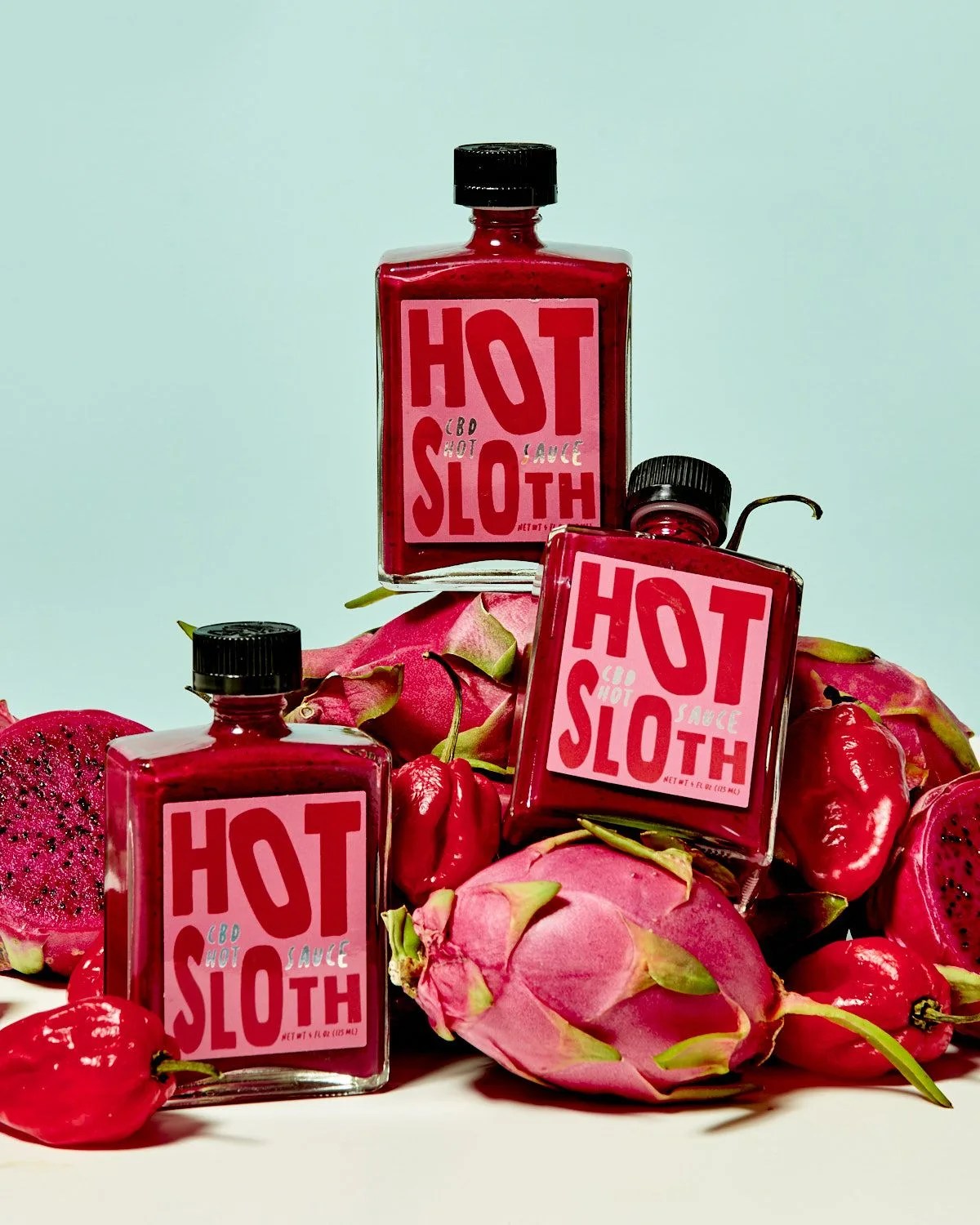 hot sloth bottles stacked on dragon fruit and peppers