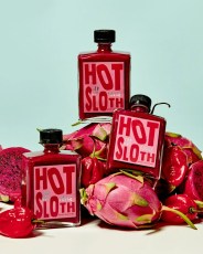 hot sloth bottles stacked on dragon fruit and peppers
