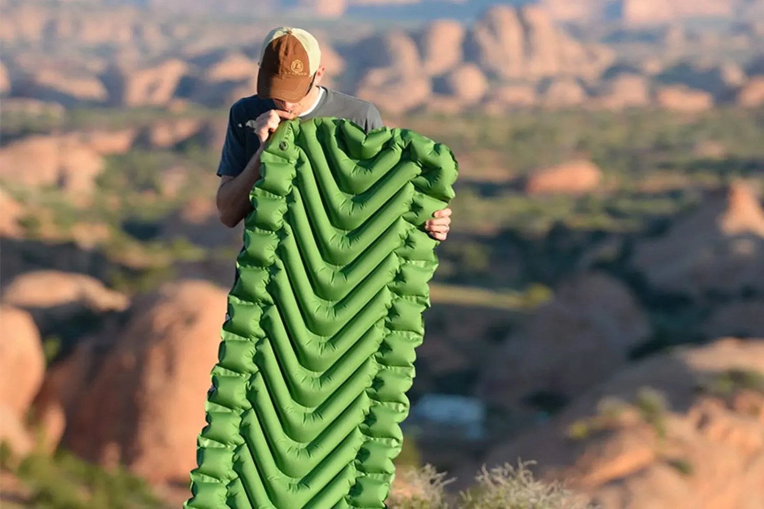 a man blowing up a camping mattress