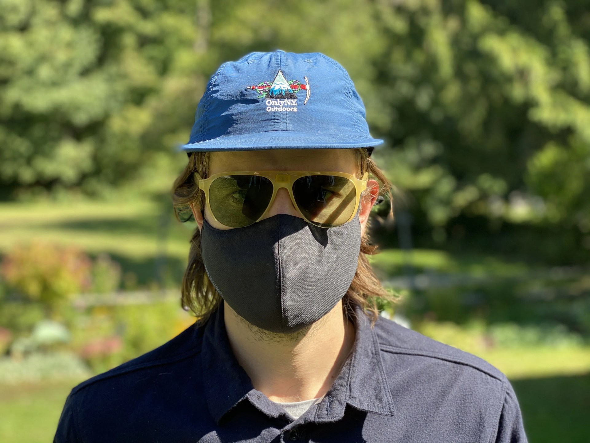 person wearing face mask, sunglasses and hat