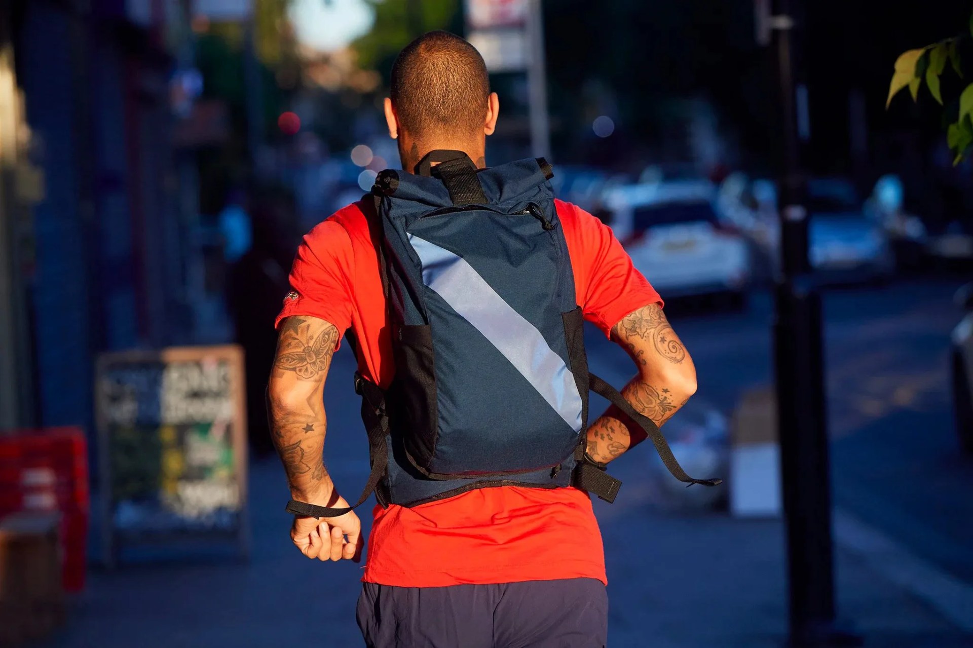 a man in a red t shirt and navy backpack running