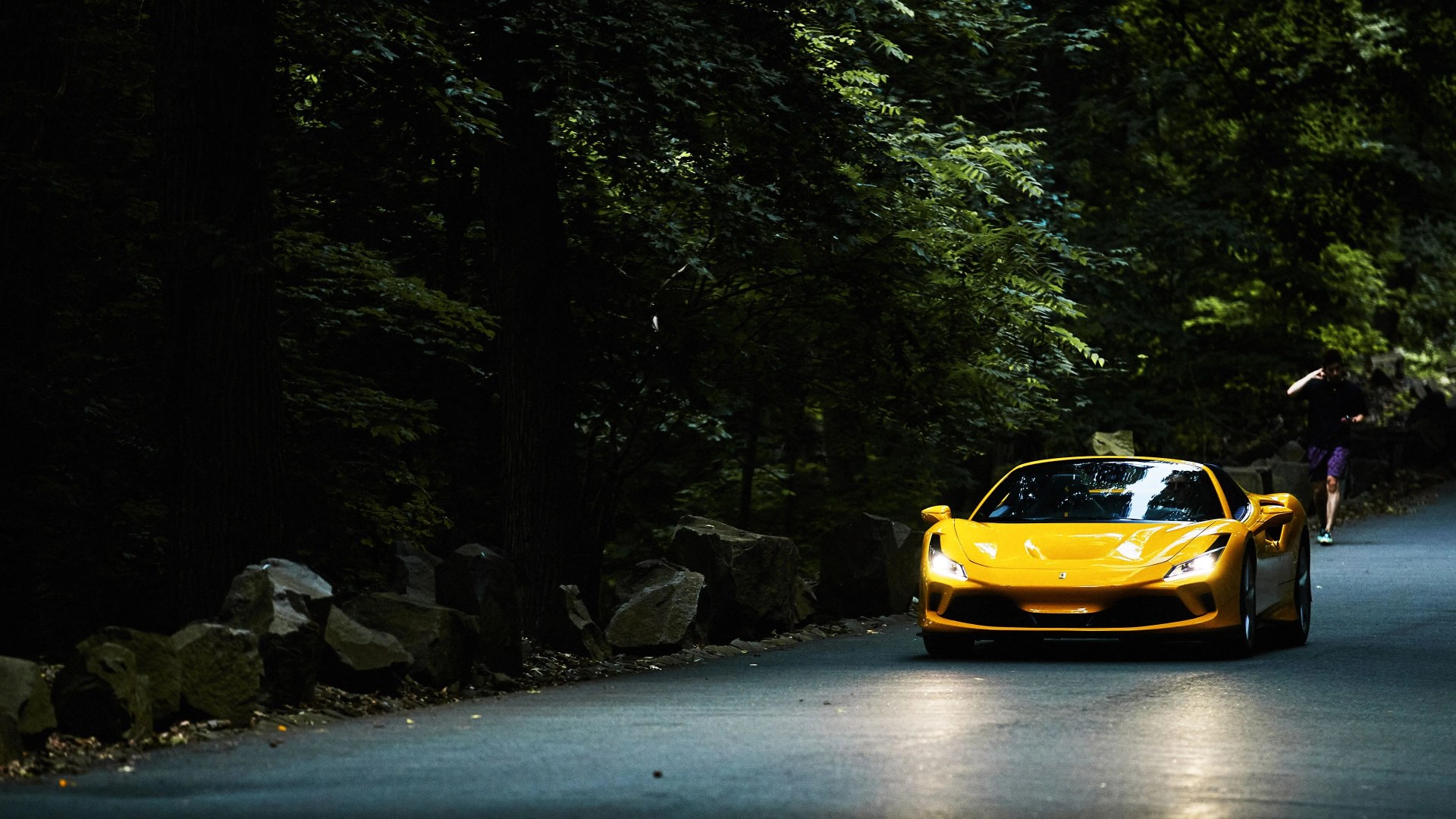 a yellow ferrari f8 spider on a dark forest road