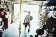 young man doing lunges with dumbbells in gym in garage
