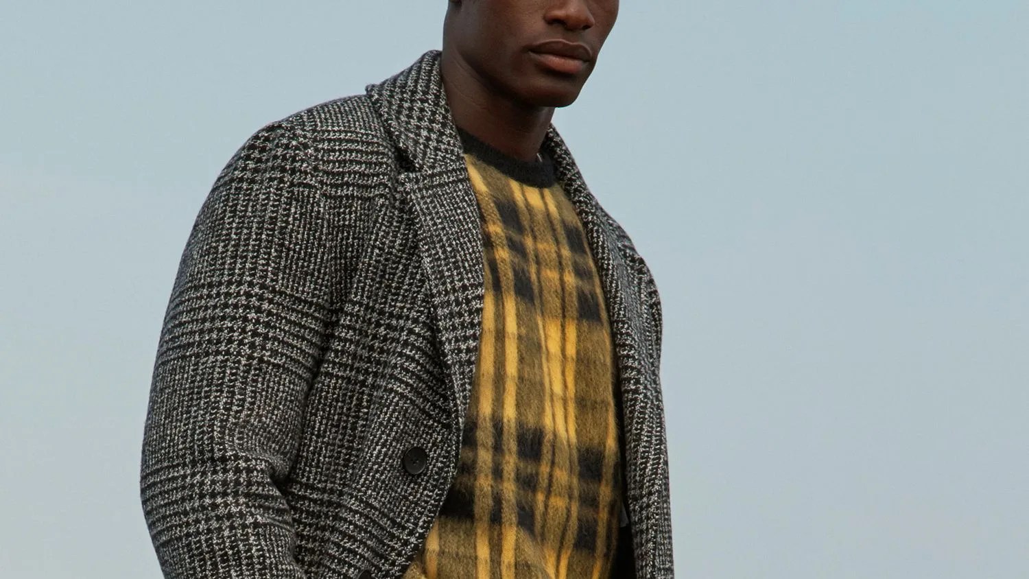 model wearing a yellow sweater and grey overcoat