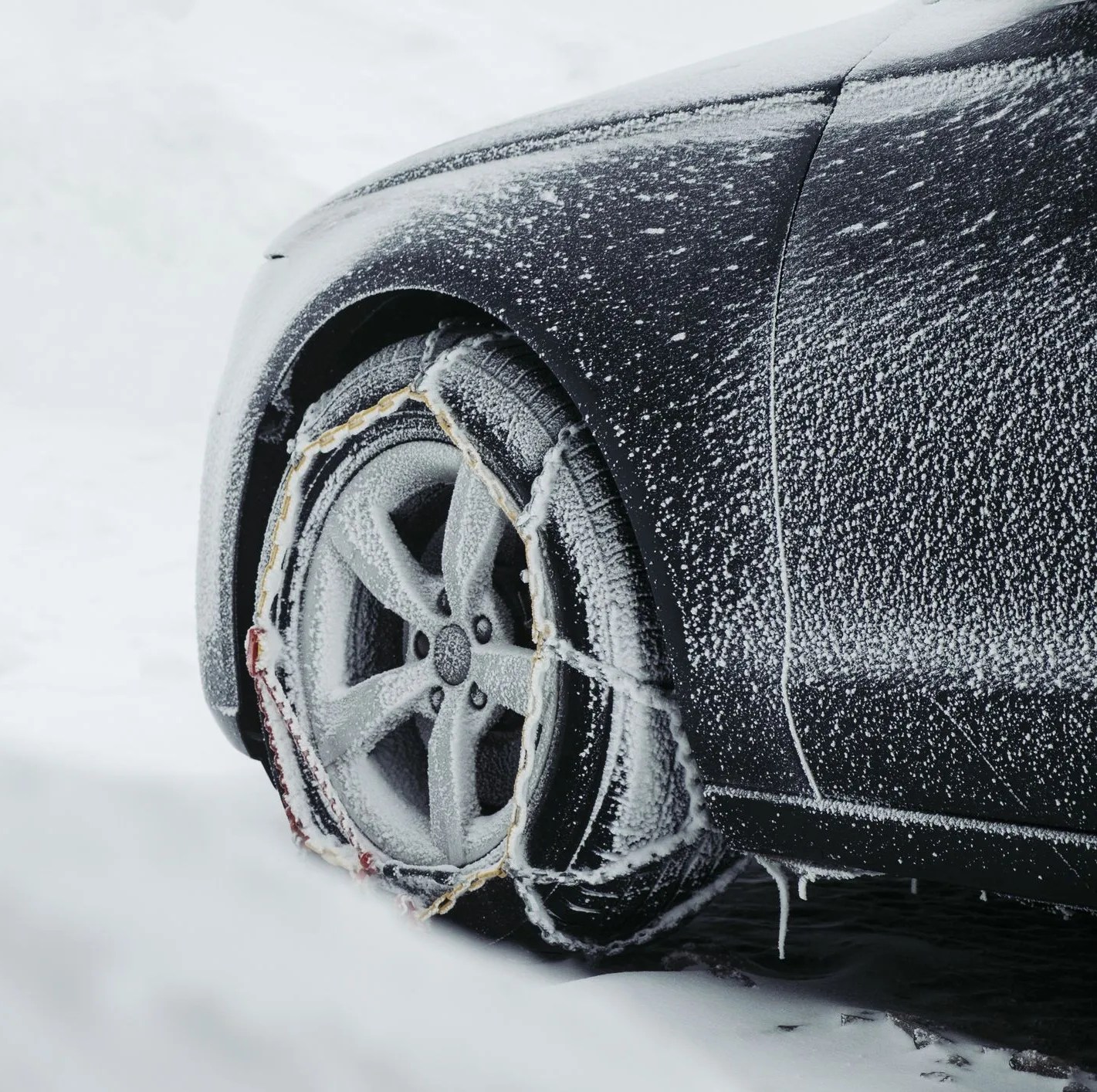 parking car in the snow with snow chains in front of a wood cabin