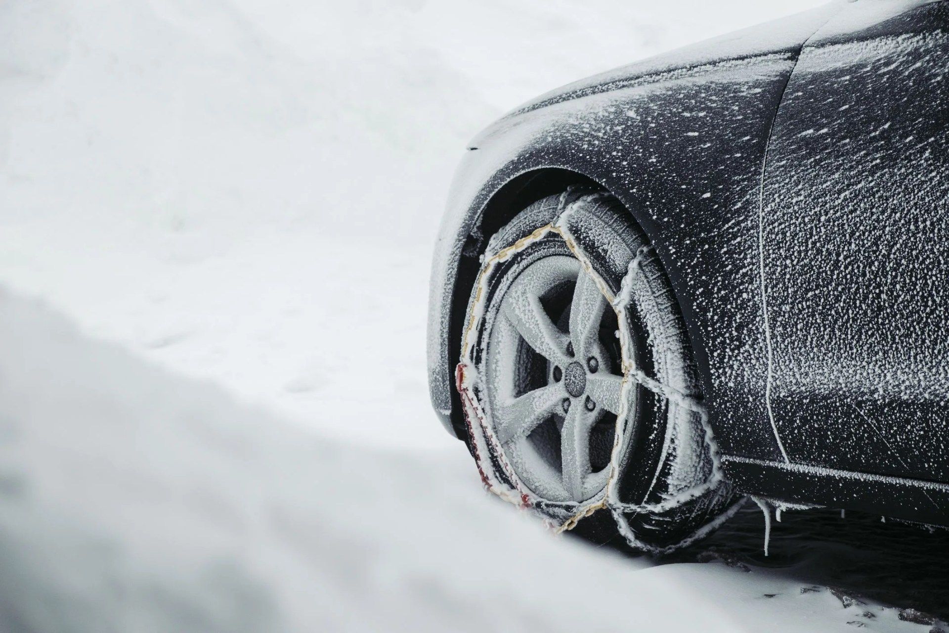 parking car in the snow with snow chains in front of a wood cabin