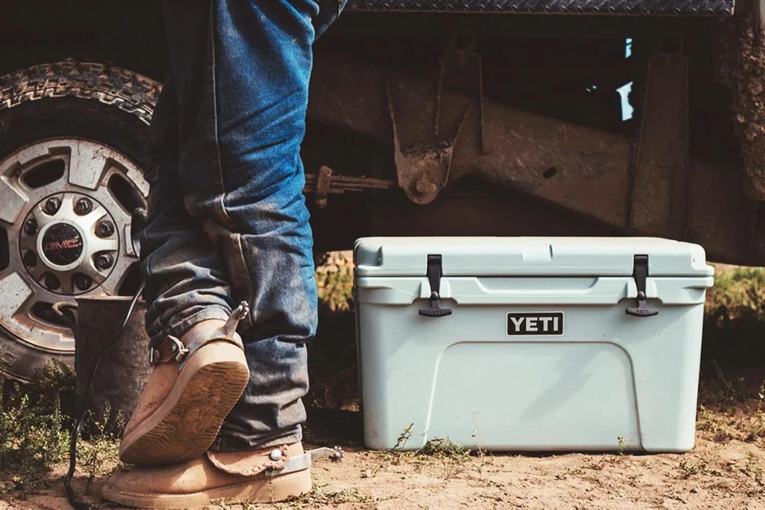 a teal cooler next to a man's legs