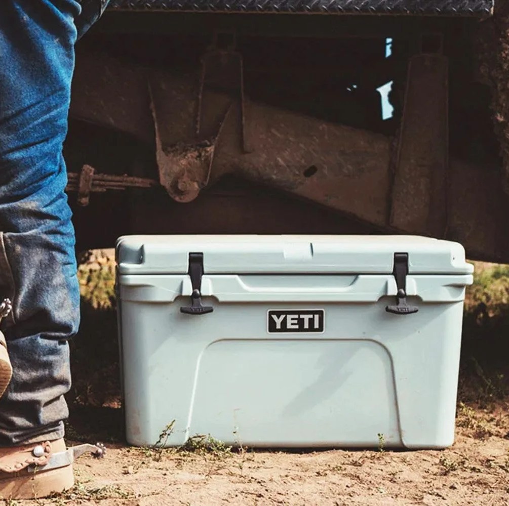 a teal cooler next to a man's legs