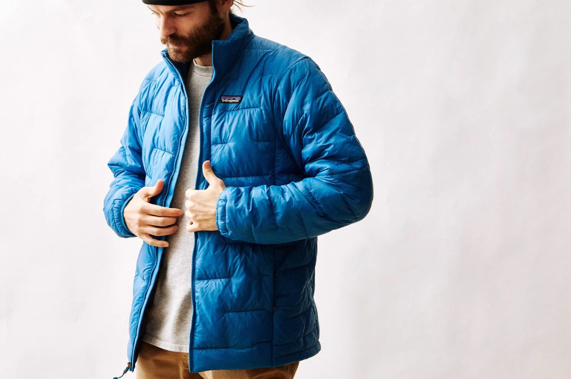 a man wearing a blue patagonia puffy jacket on a blank background