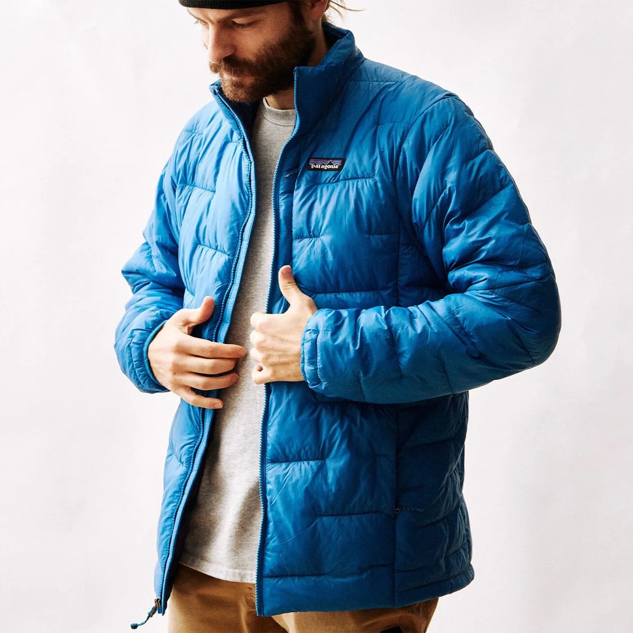 a man wearing a blue patagonia puffy jacket on a blank background