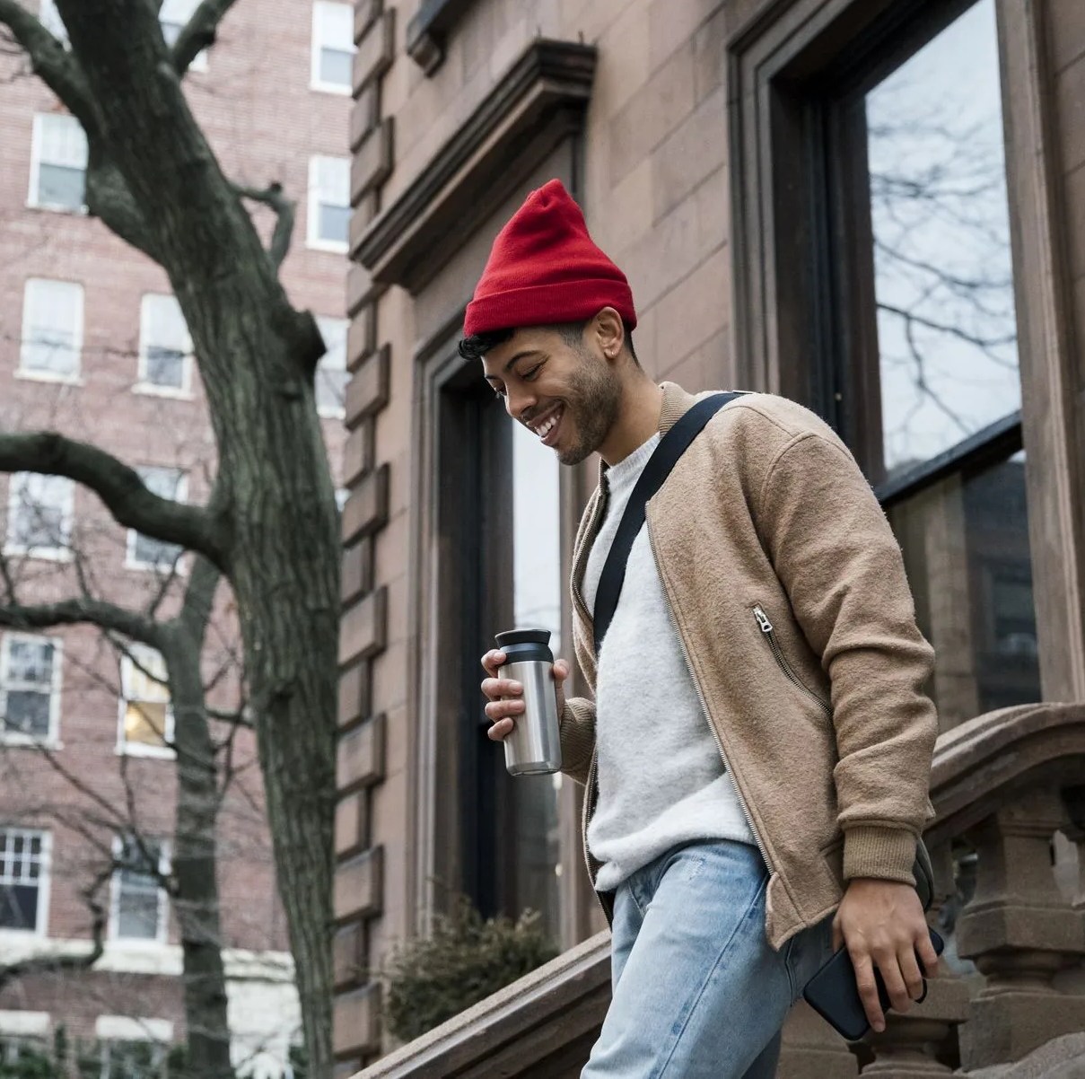 cheerful young man walking down steps at brownstone
