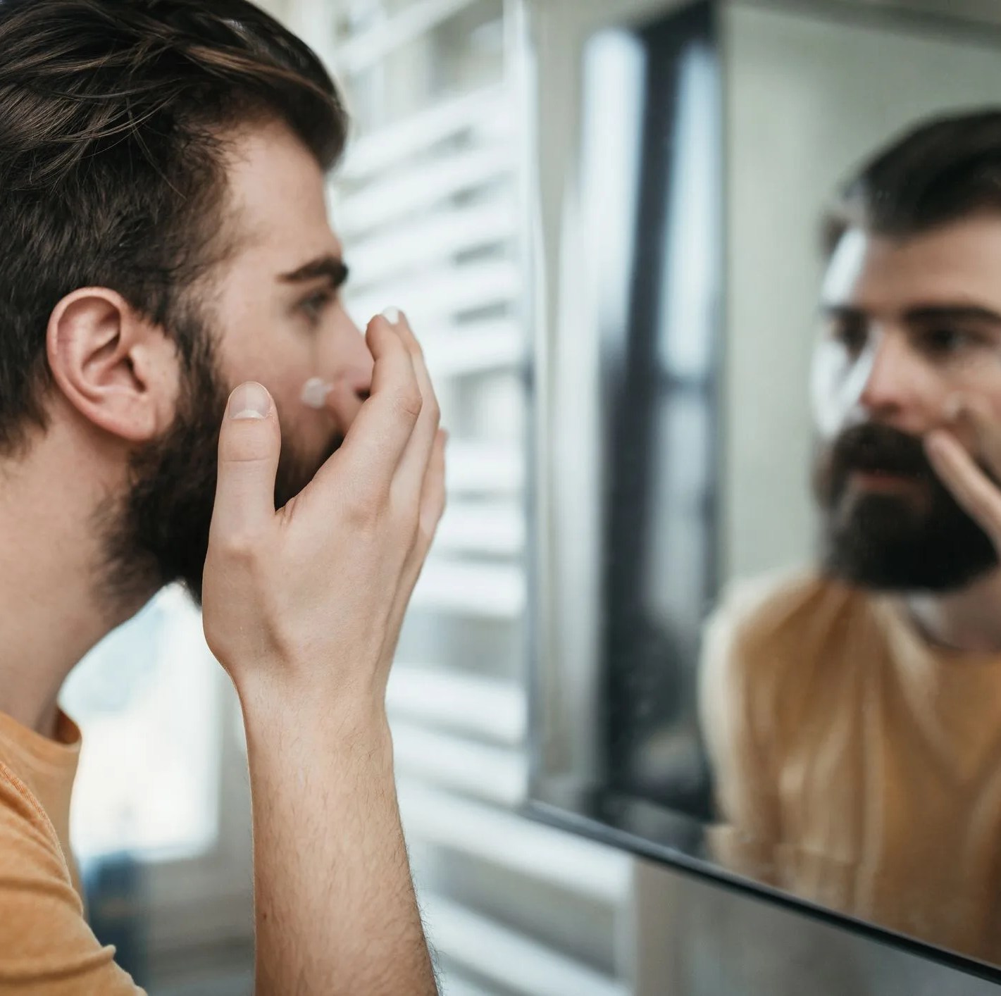 handsome man applying face cream in the bathroom