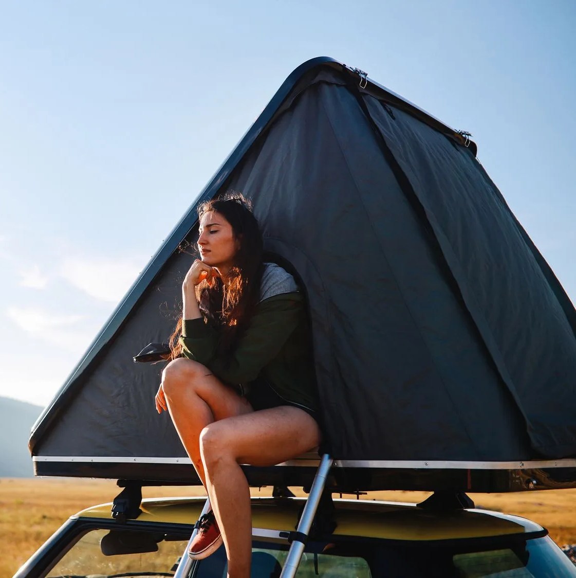 panoramic portrait of a young woman relaxing in a car rooftop tent