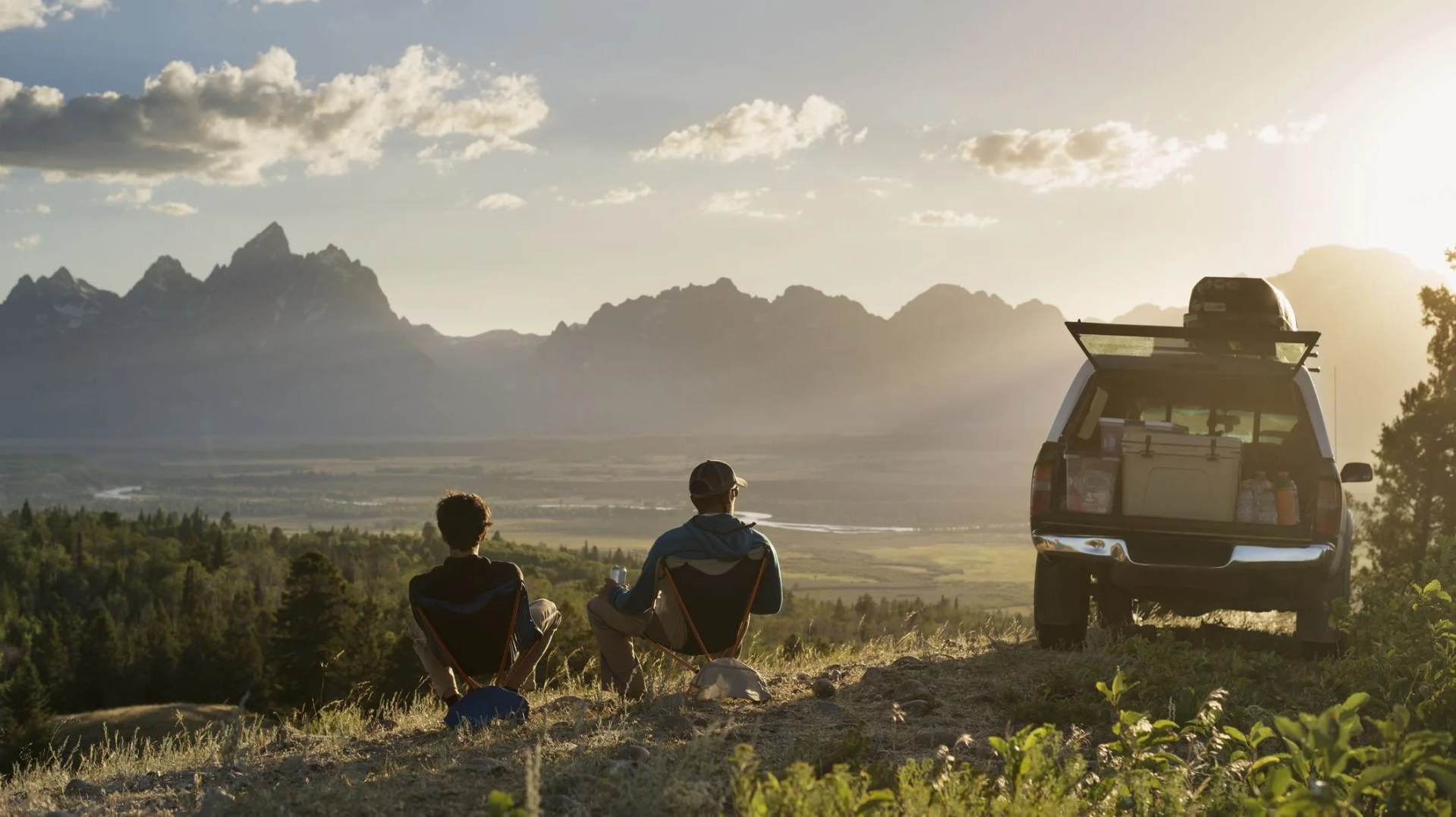 rear view of male hikers relaxing on reclining chair in field