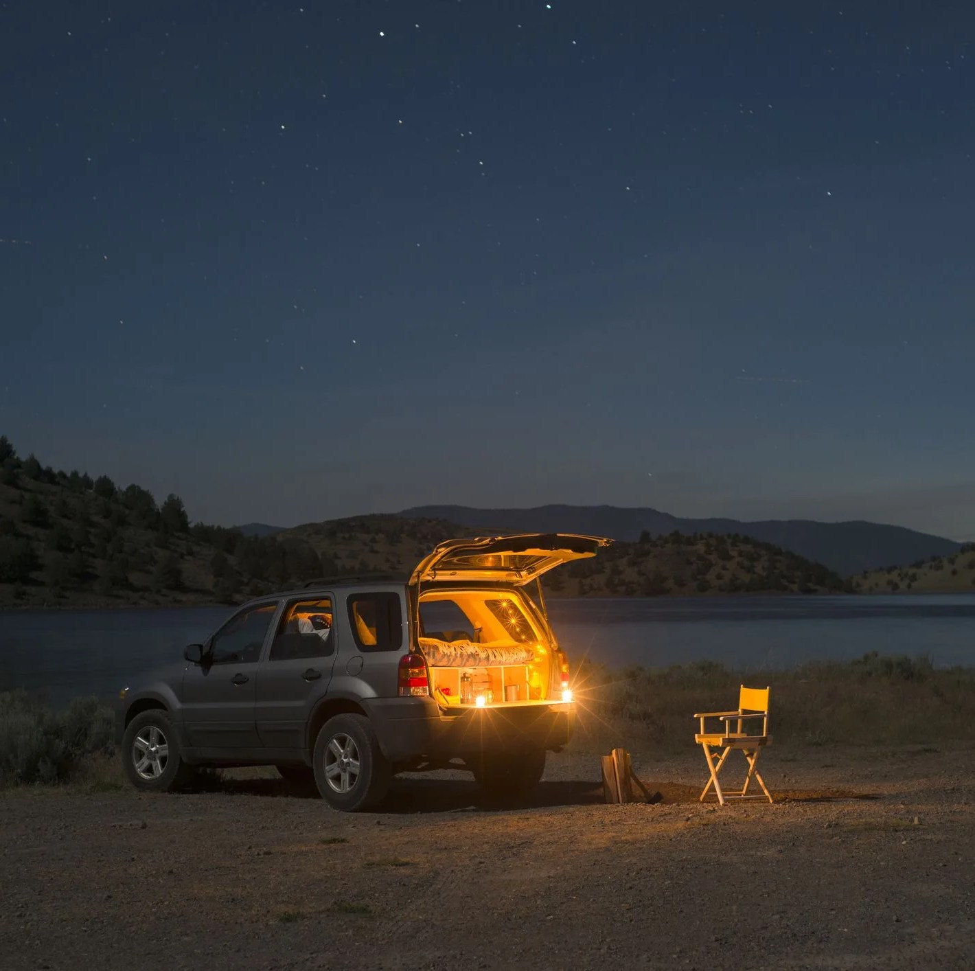 sports utility vehicle parked on shore by lake shastina against sky during night