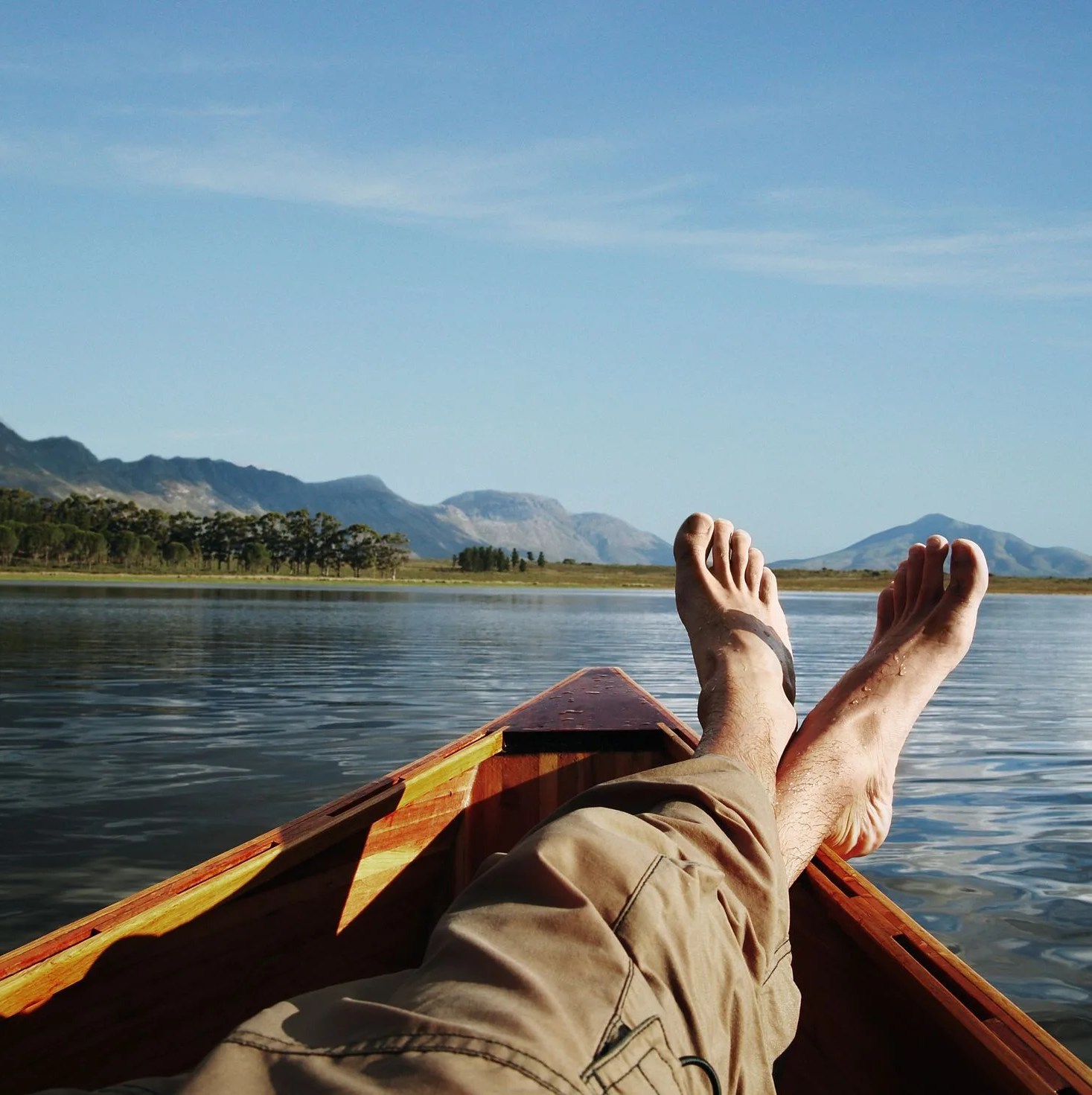 young man lying in boat on lake, low section