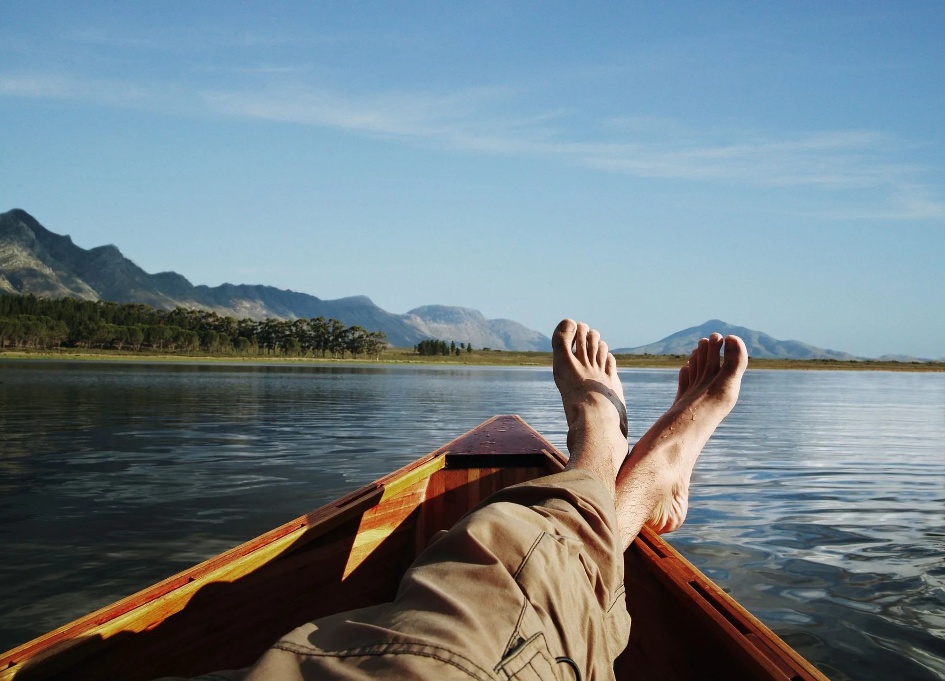 young man lying in boat on lake, low section