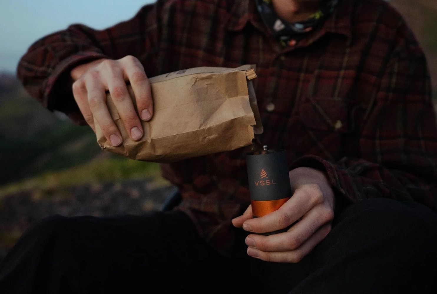 hand pouring coffee into a grinder