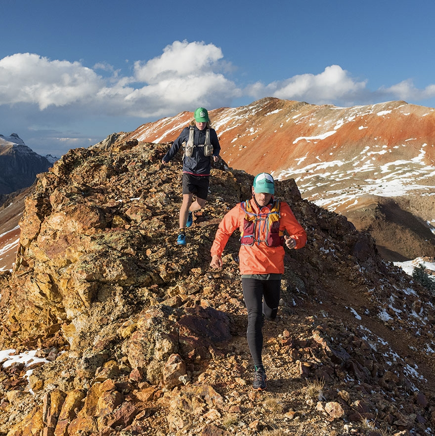 two people running on a rocky ridge