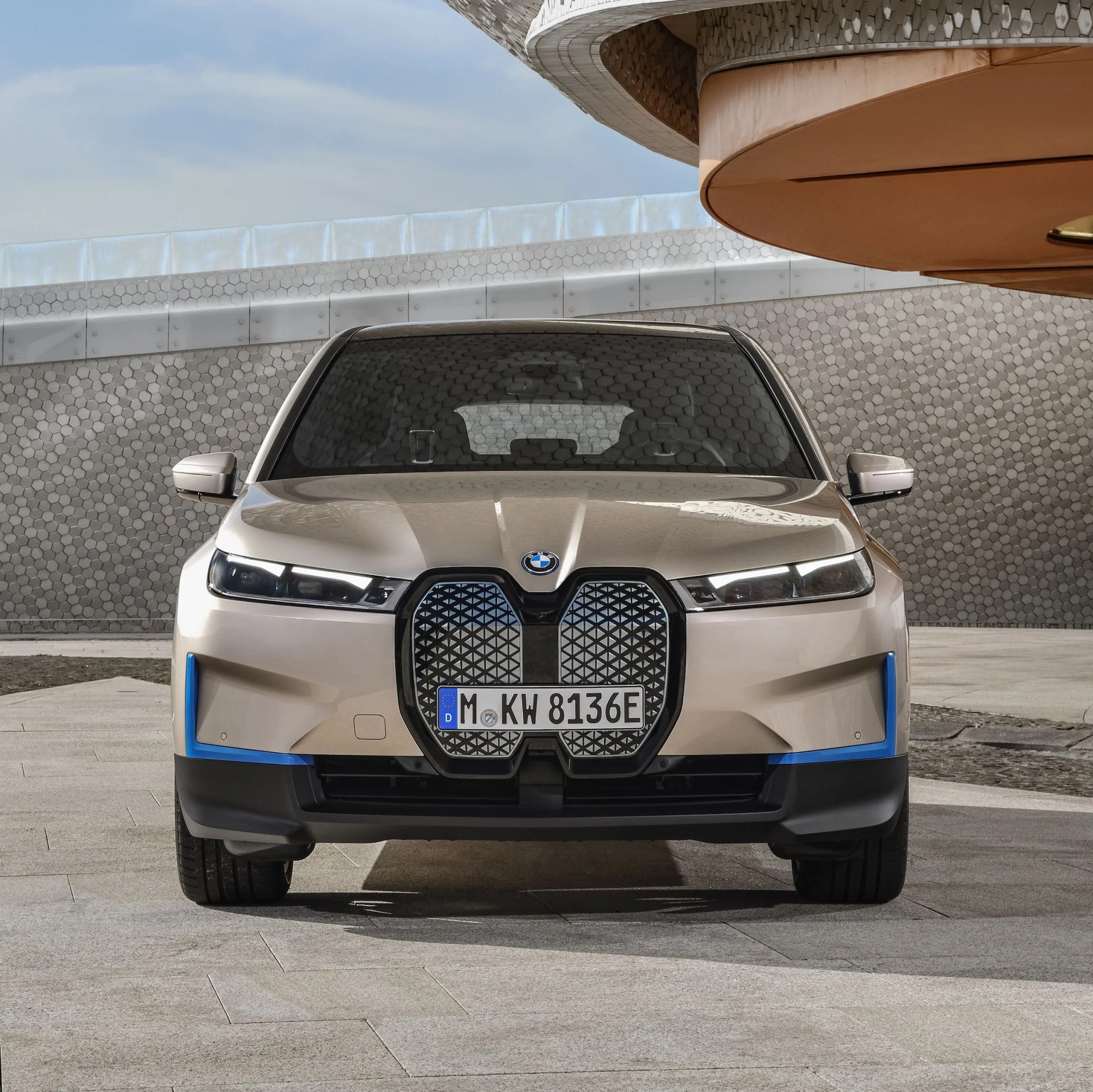 bmw ix on a stone driveway in front of a modernist building