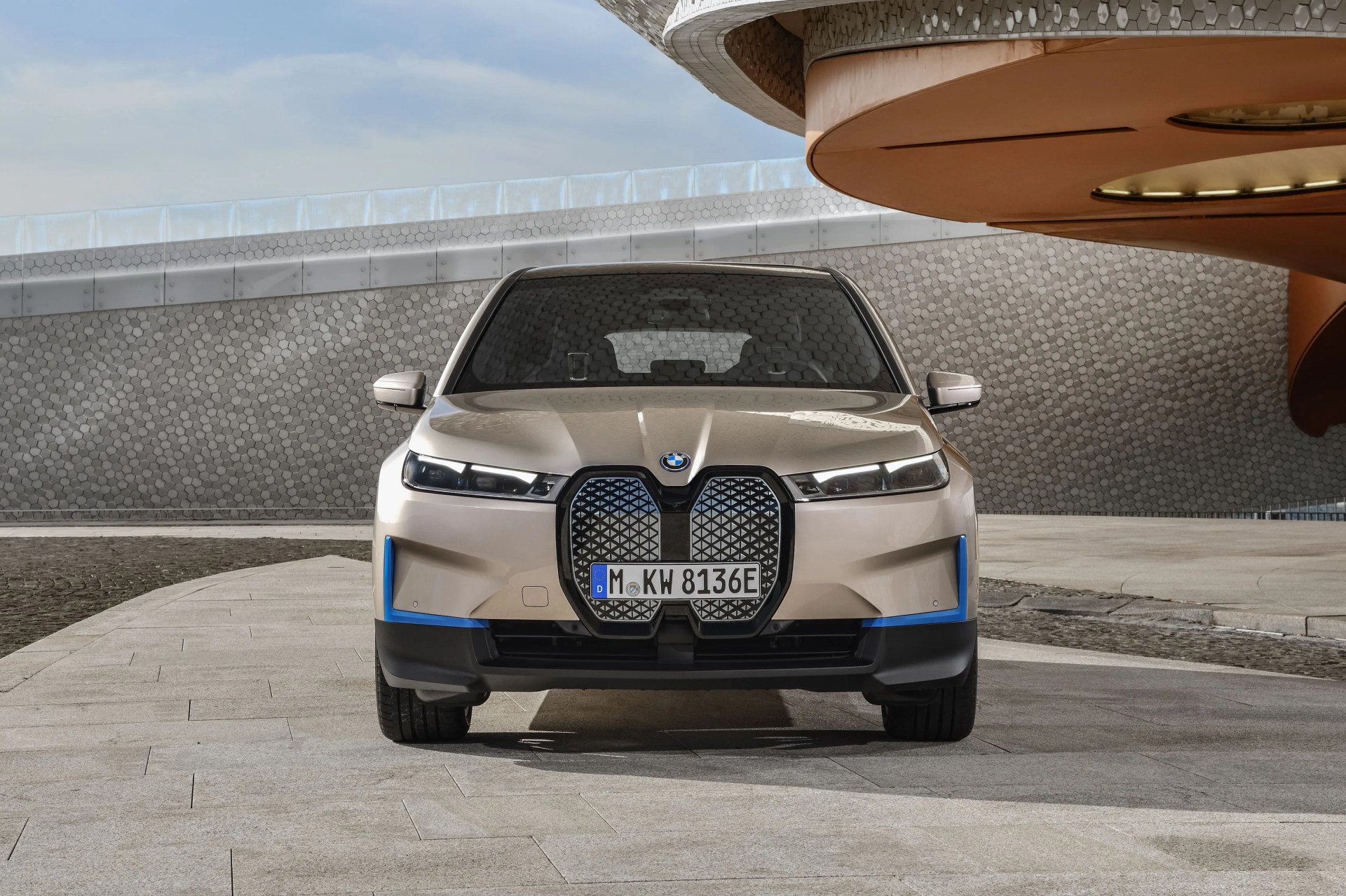 bmw ix on a stone driveway in front of a modernist building