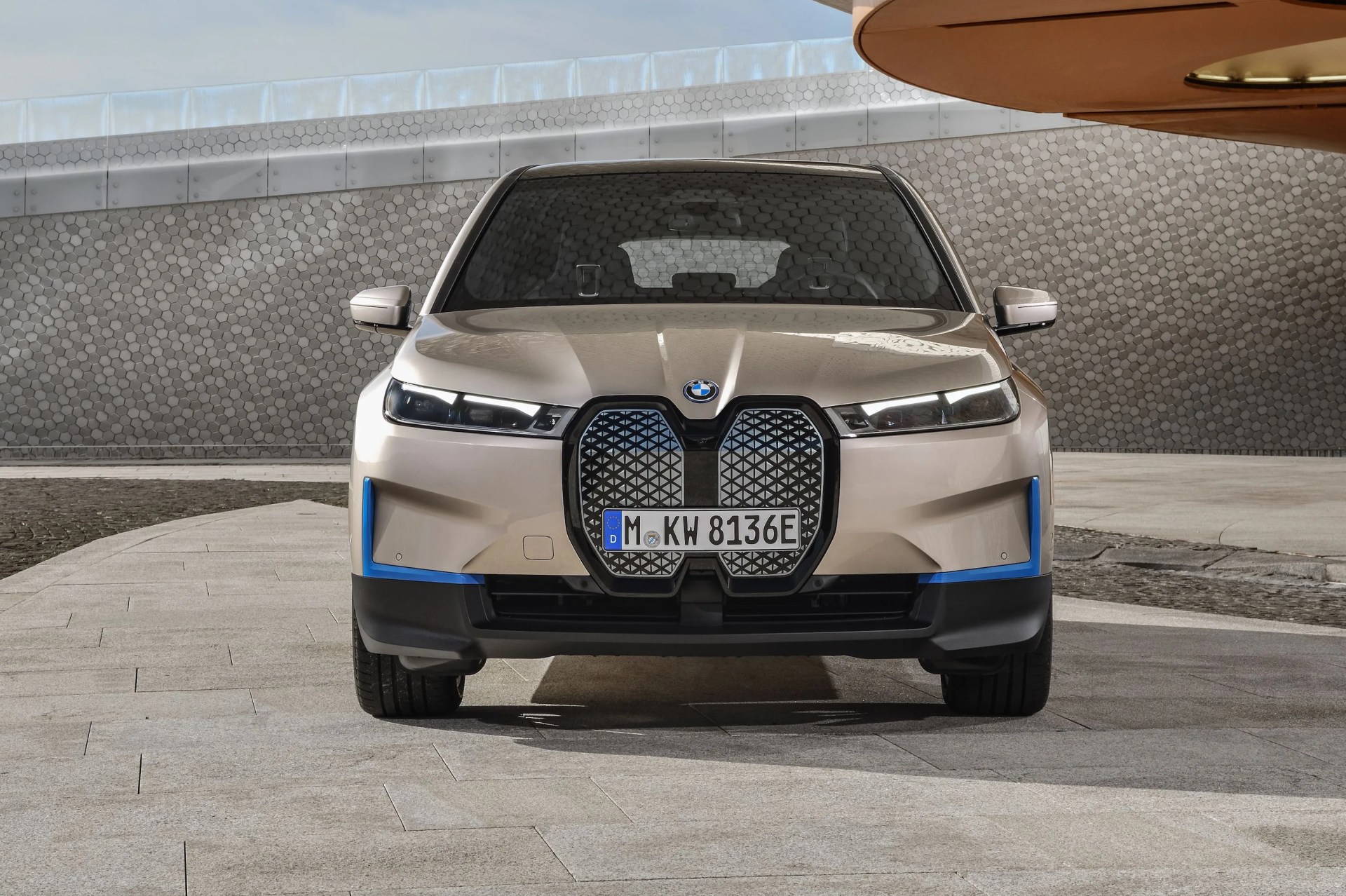 bmw ix on a stone driveway in front of a modernist building