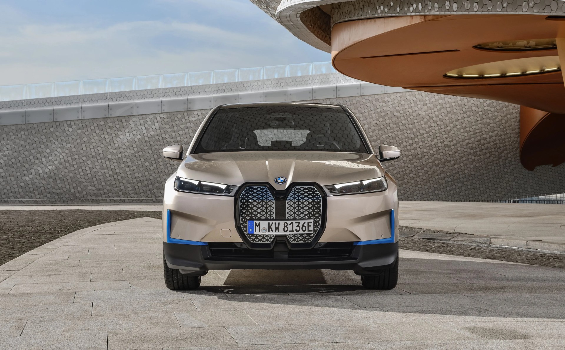 bmw ix on a stone driveway in front of a modernist building