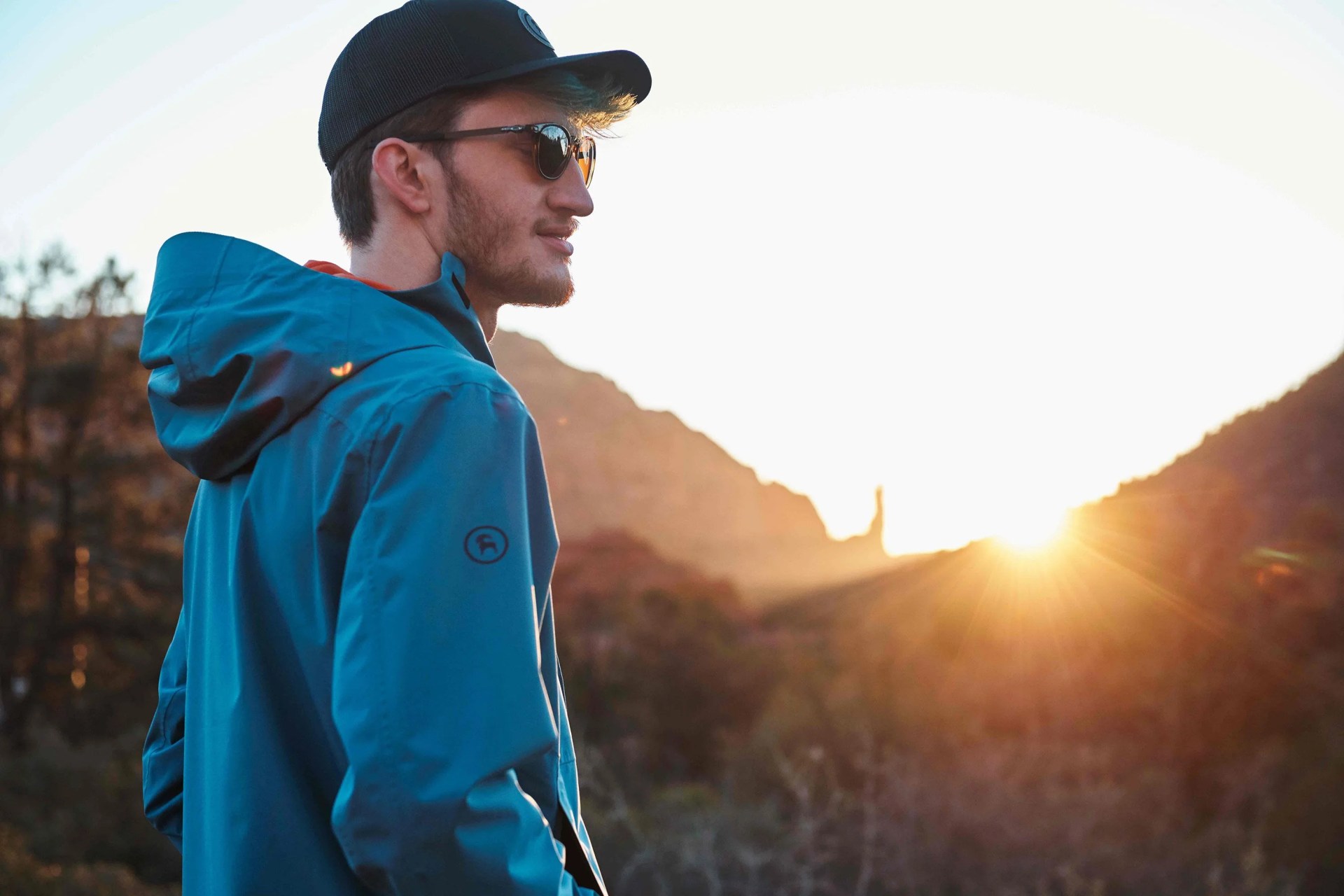 man wearing backcountry jacket looking into the distance as the sun sets