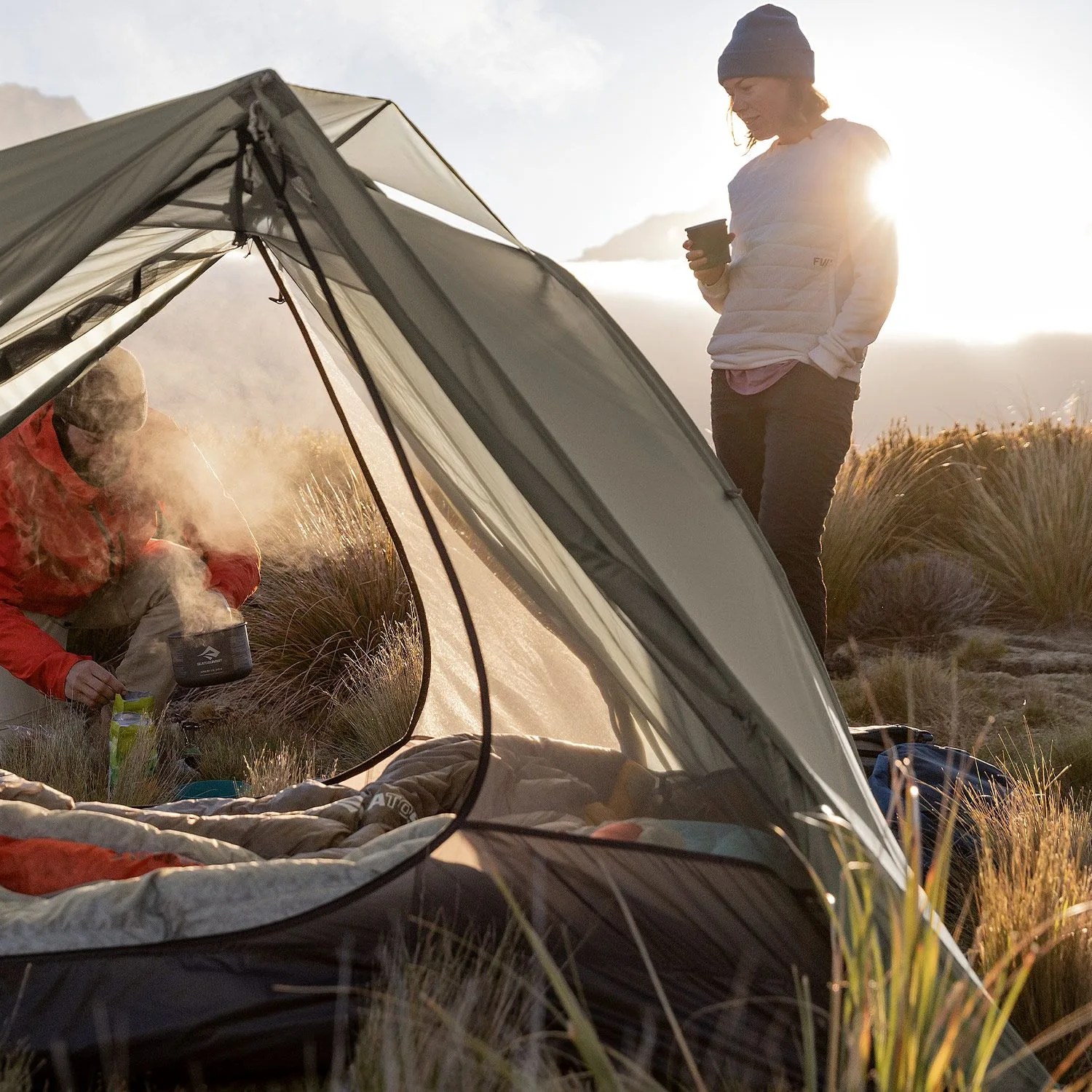 two people camping with a gray tent