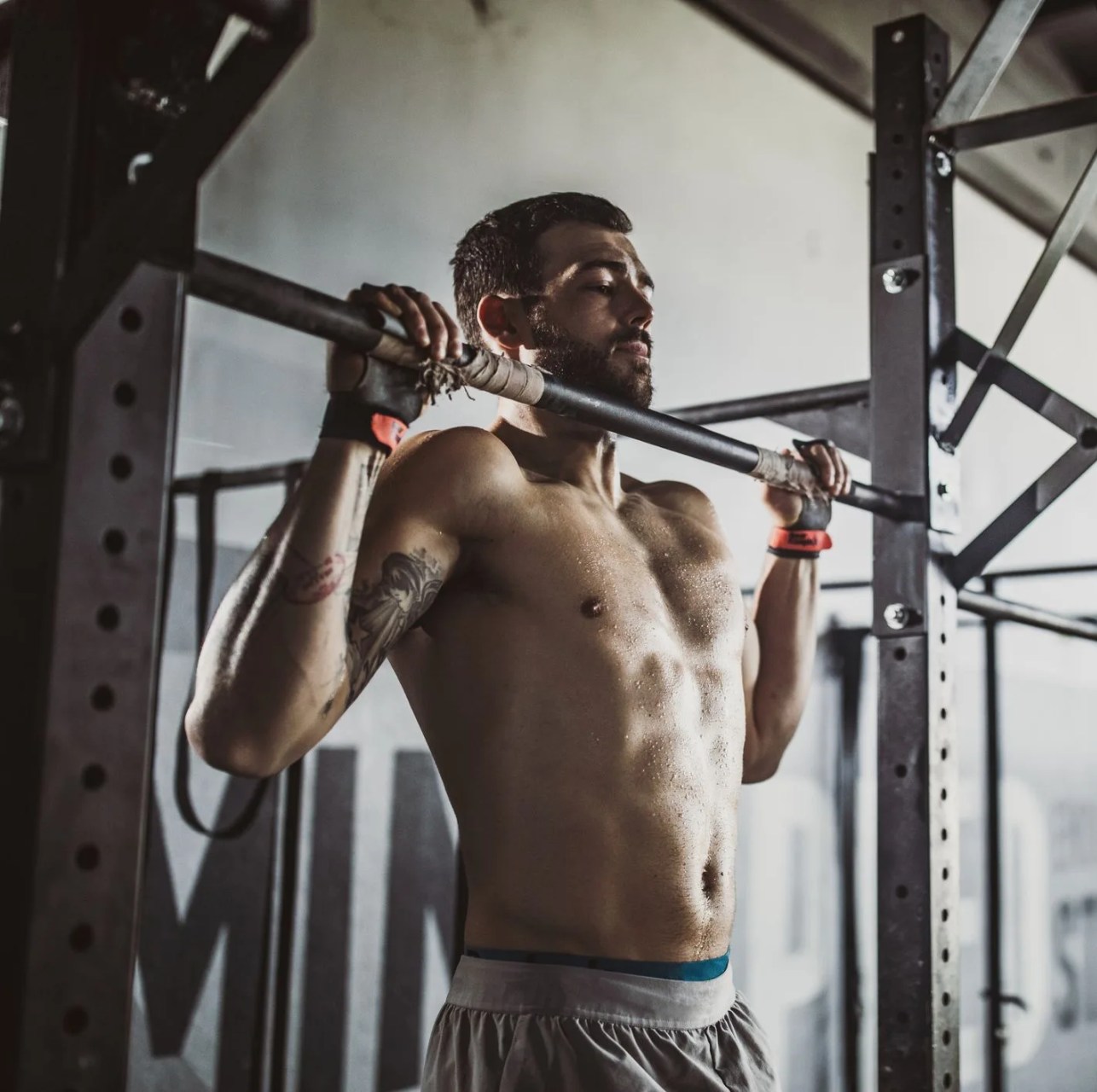 young muscular build athlete exercising pullups in a gym
