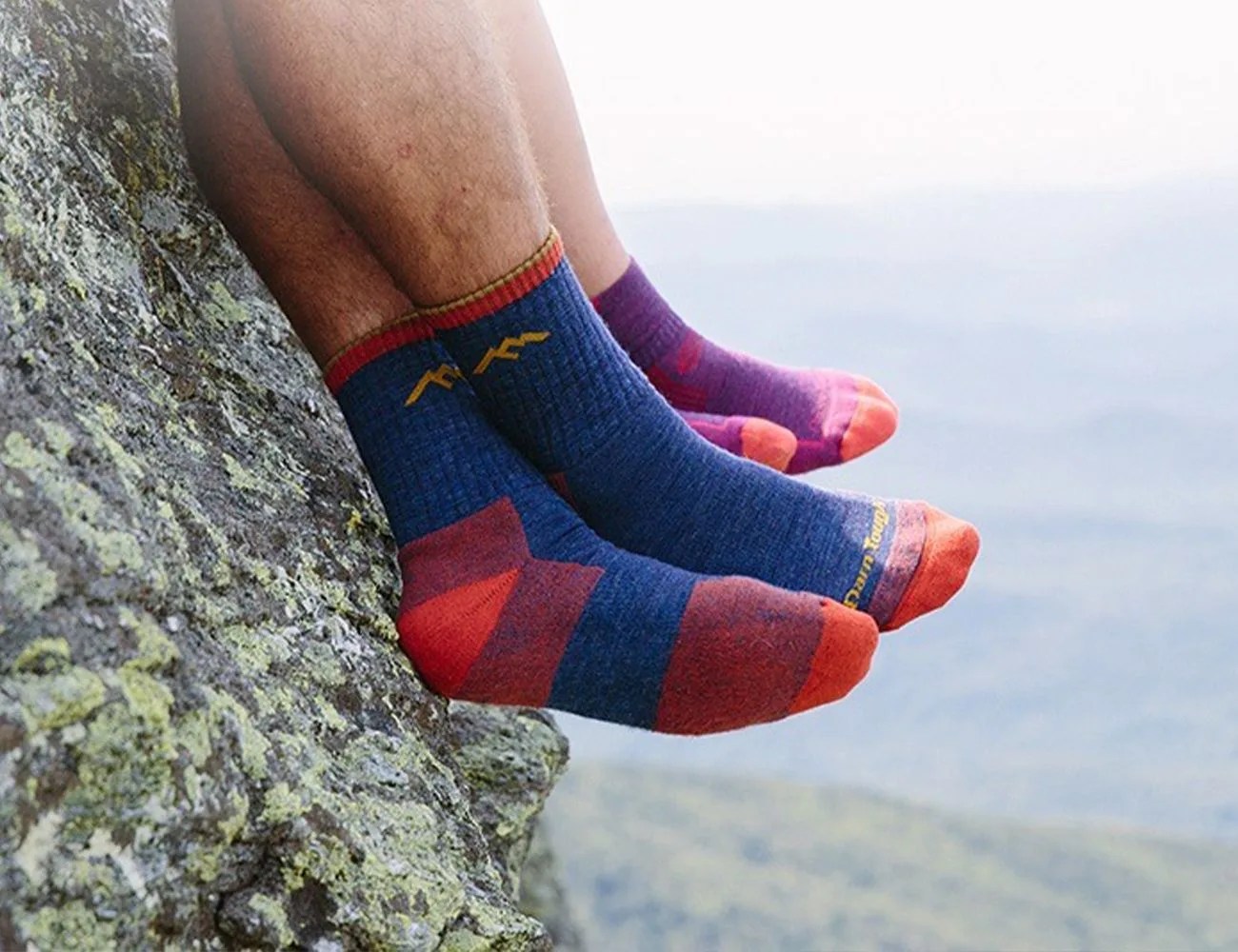 couple sitting on a mountain edge wearing darn tough socks