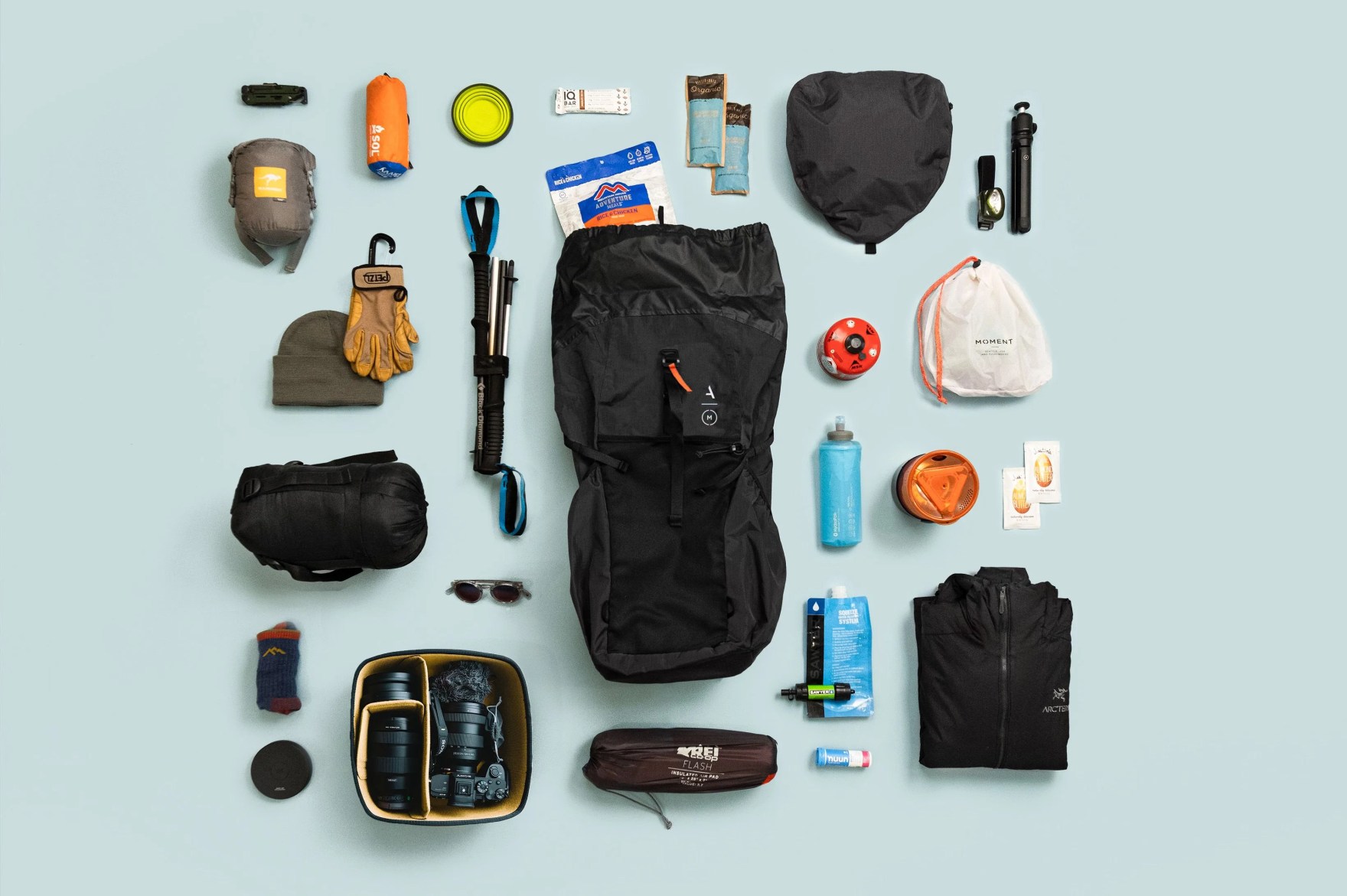 a backpack with all its contents spread out beside it