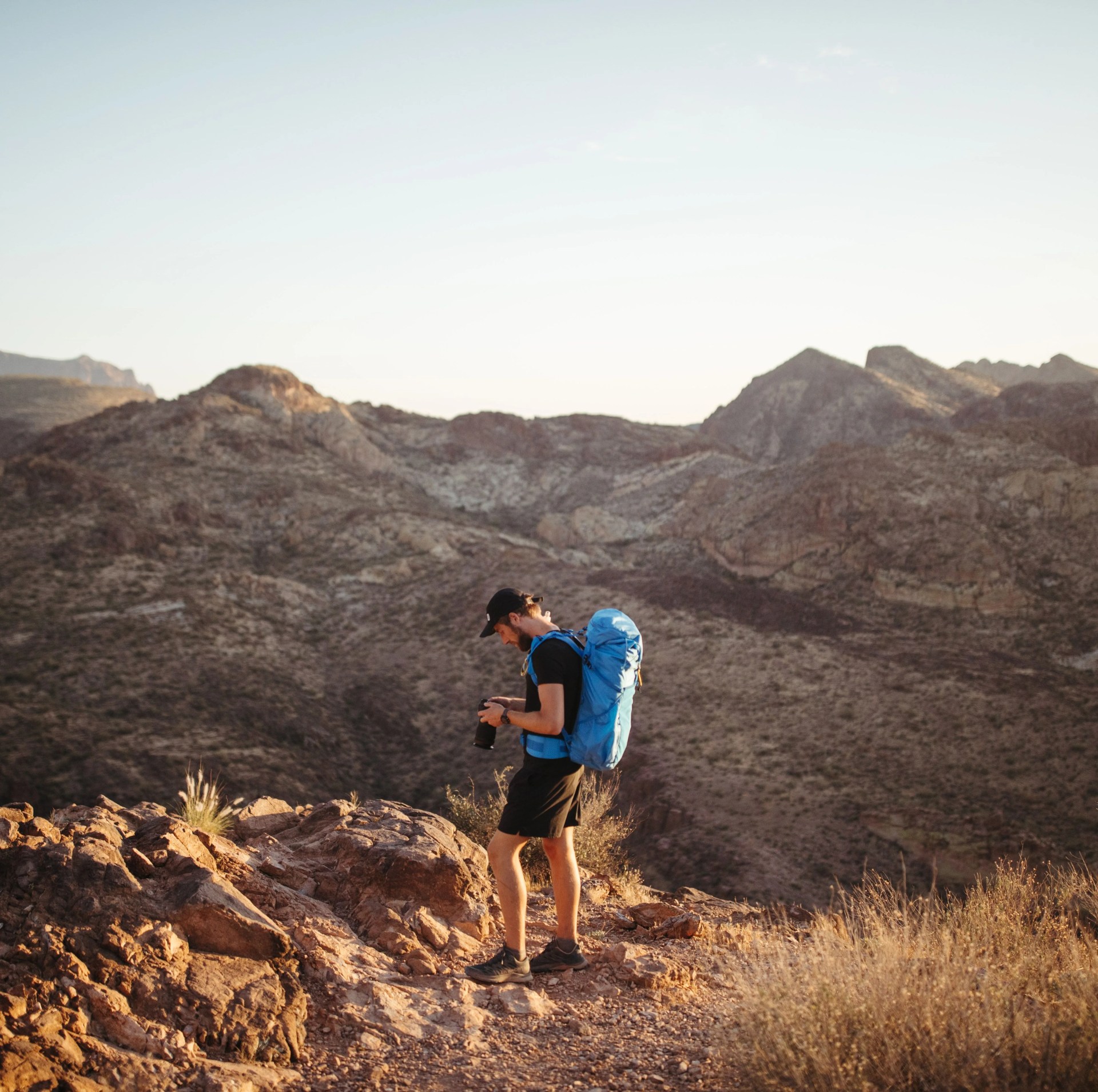 a man with a blue backpack in the desert