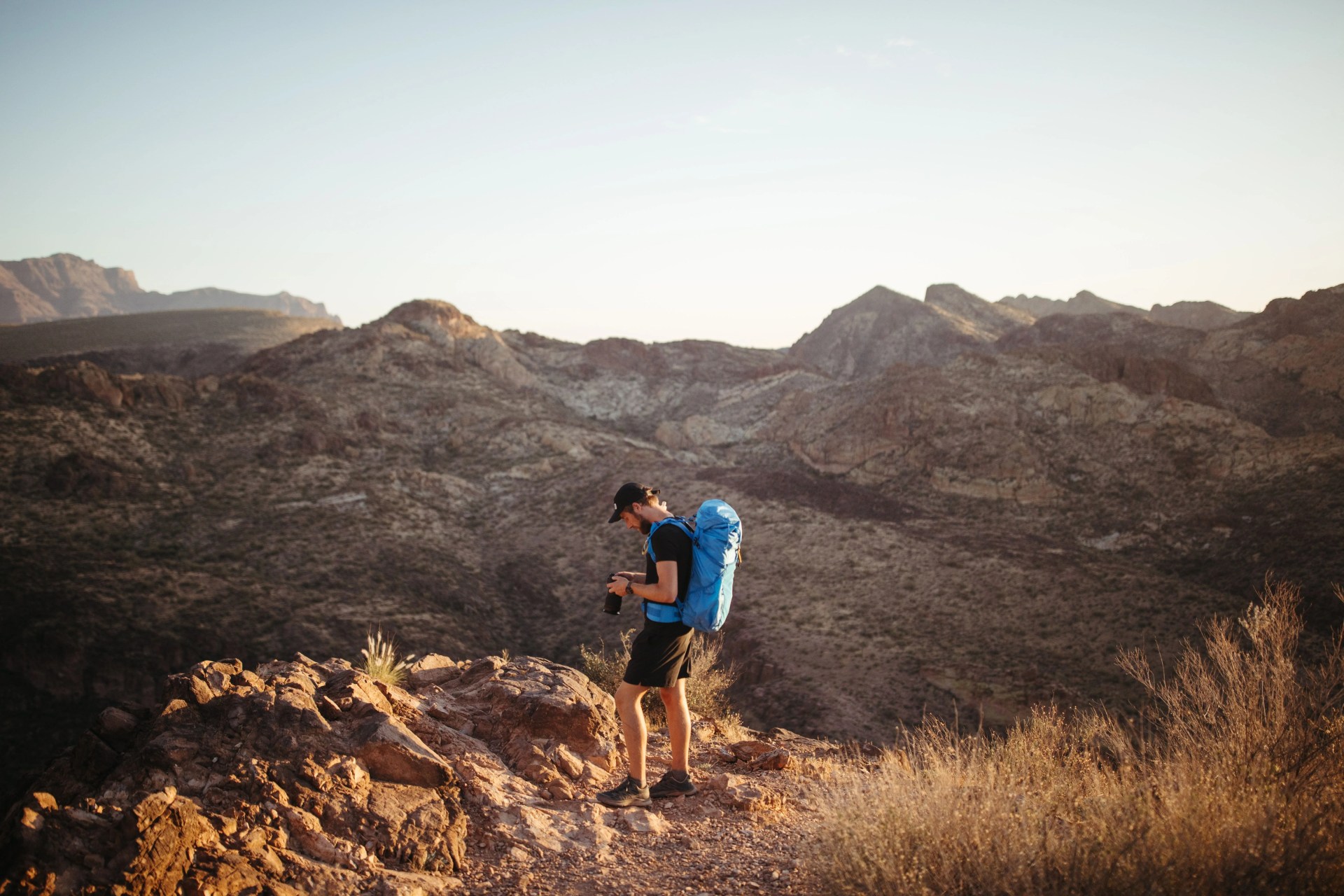a man with a blue backpack in the desert