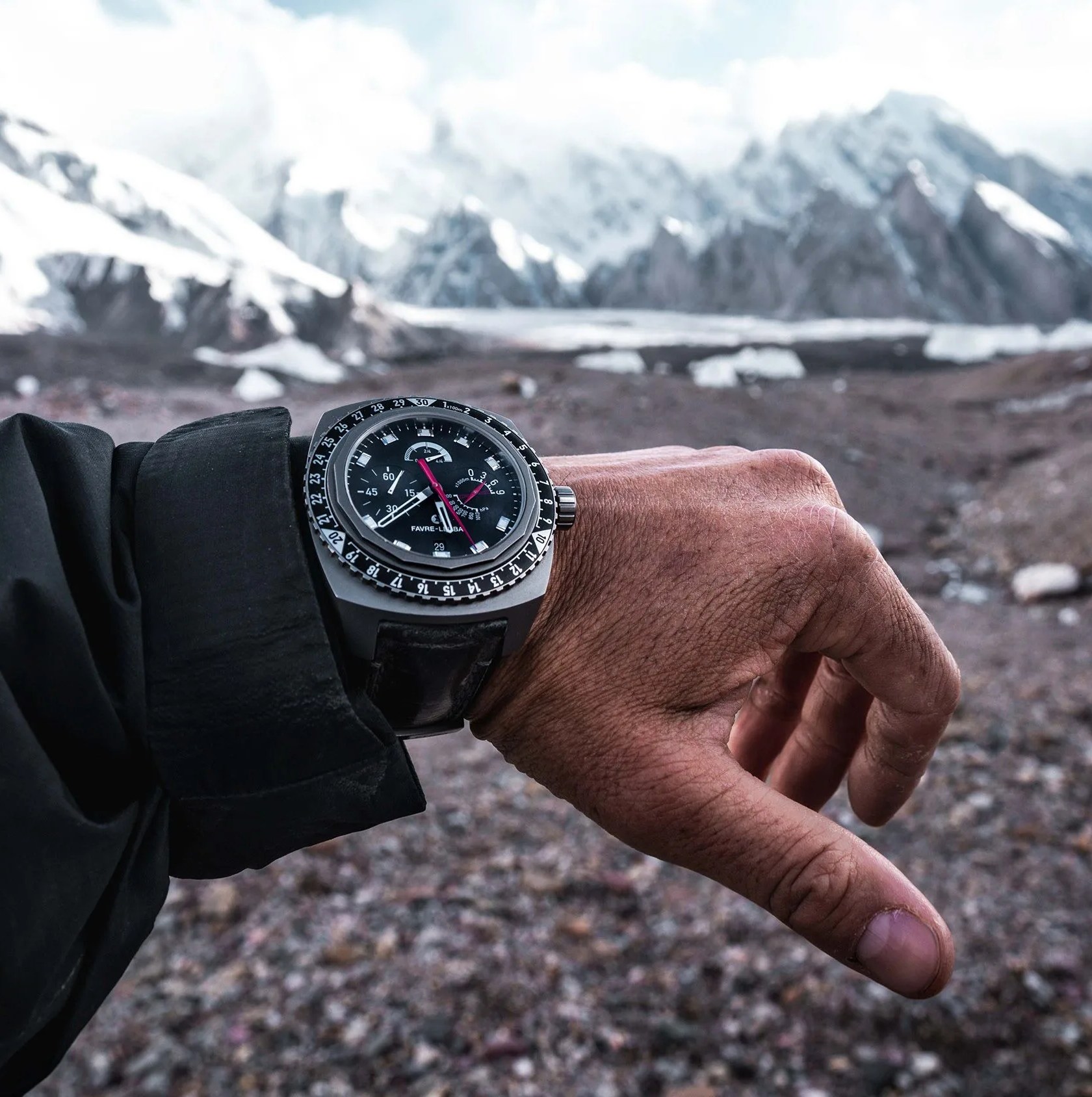 man wearing watch on wrist with mountains in the background