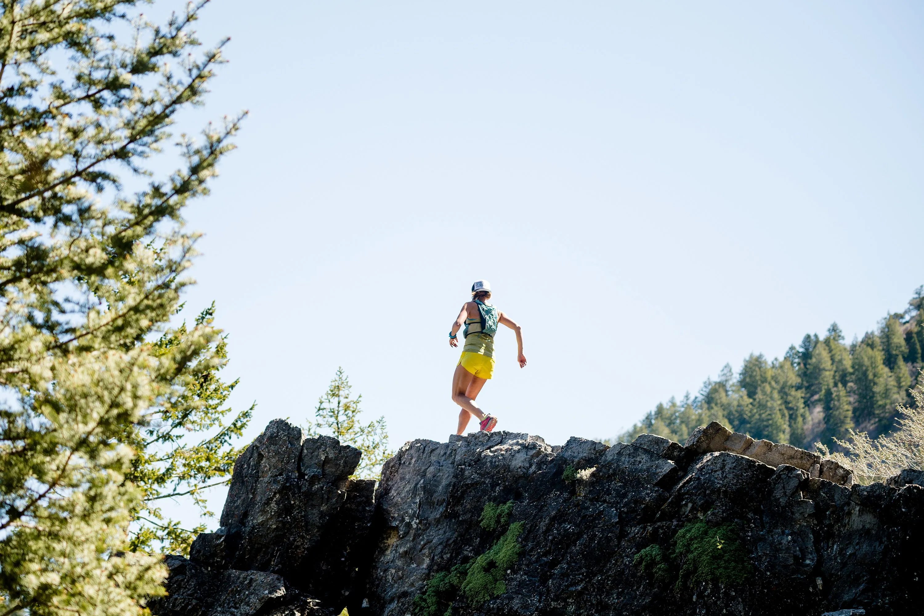 woman walking along cliff edge wearing backcountry gear