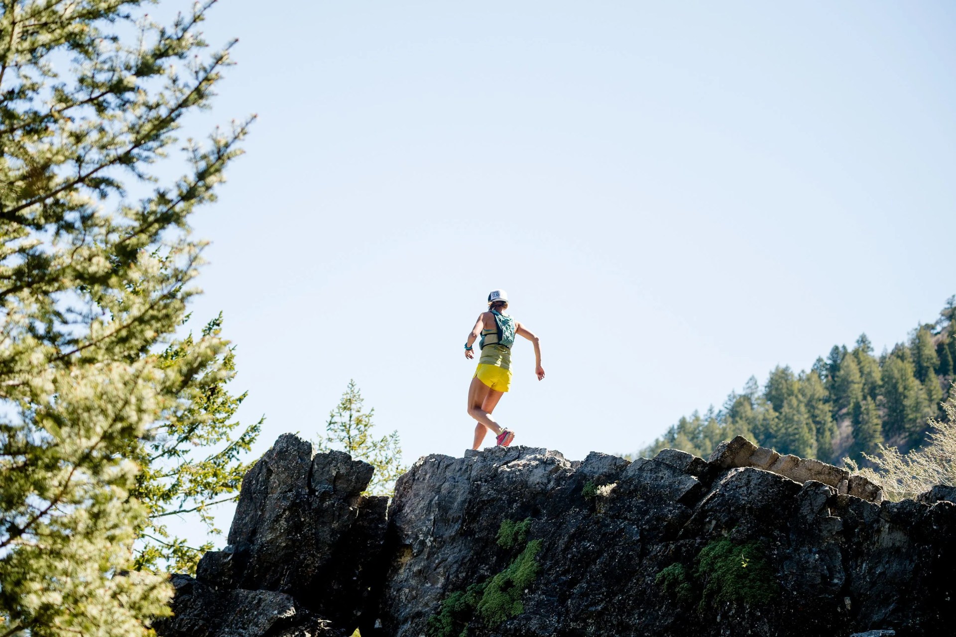 woman walking along cliff edge wearing backcountry gear