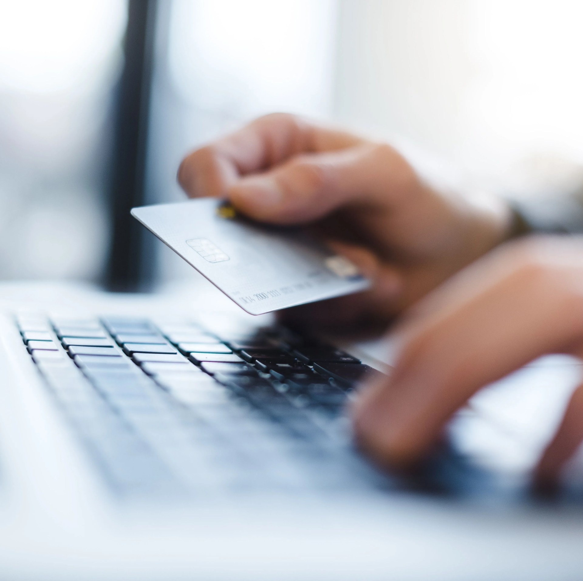 man using laptop and holding credit card closeup