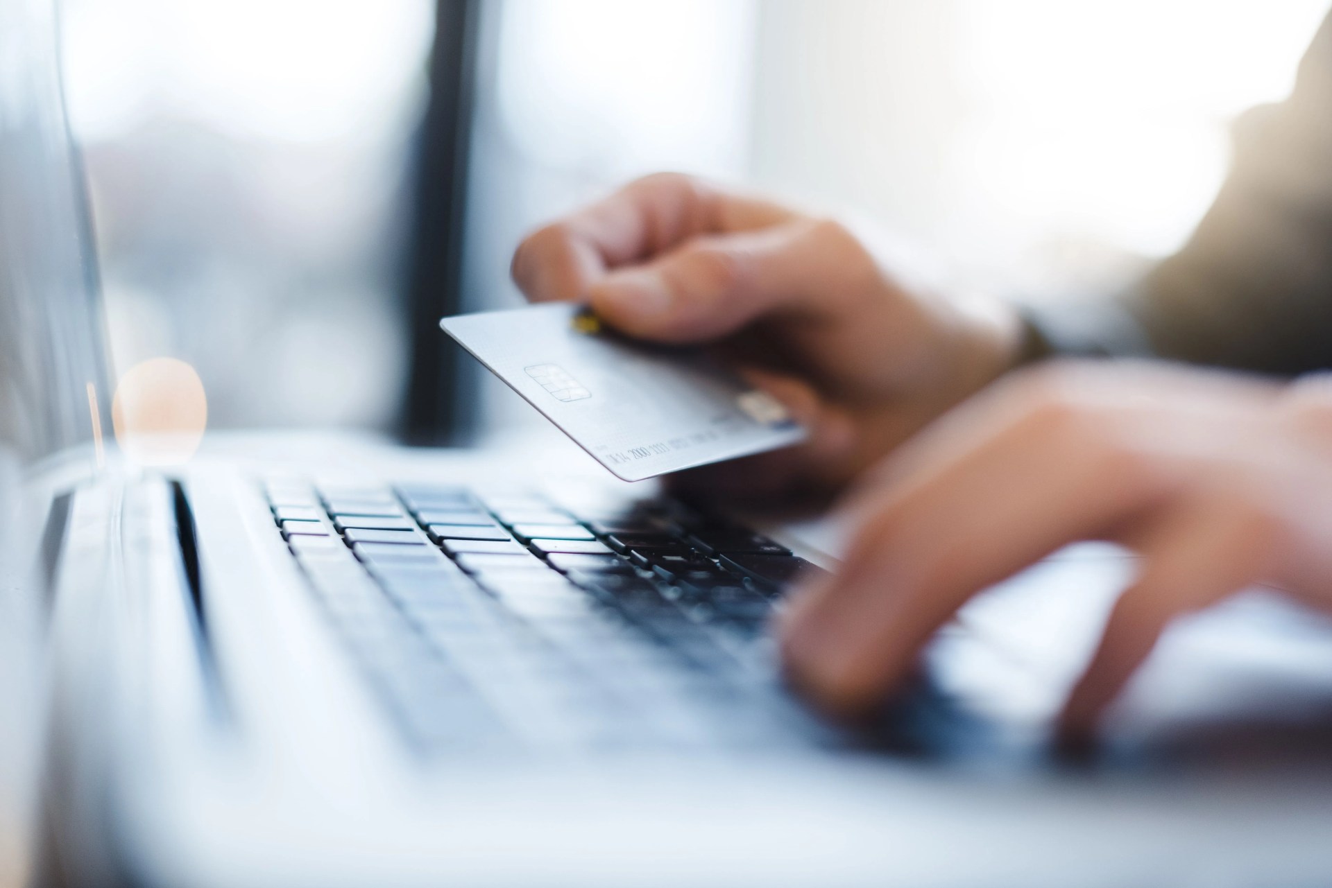 man using laptop and holding credit card closeup
