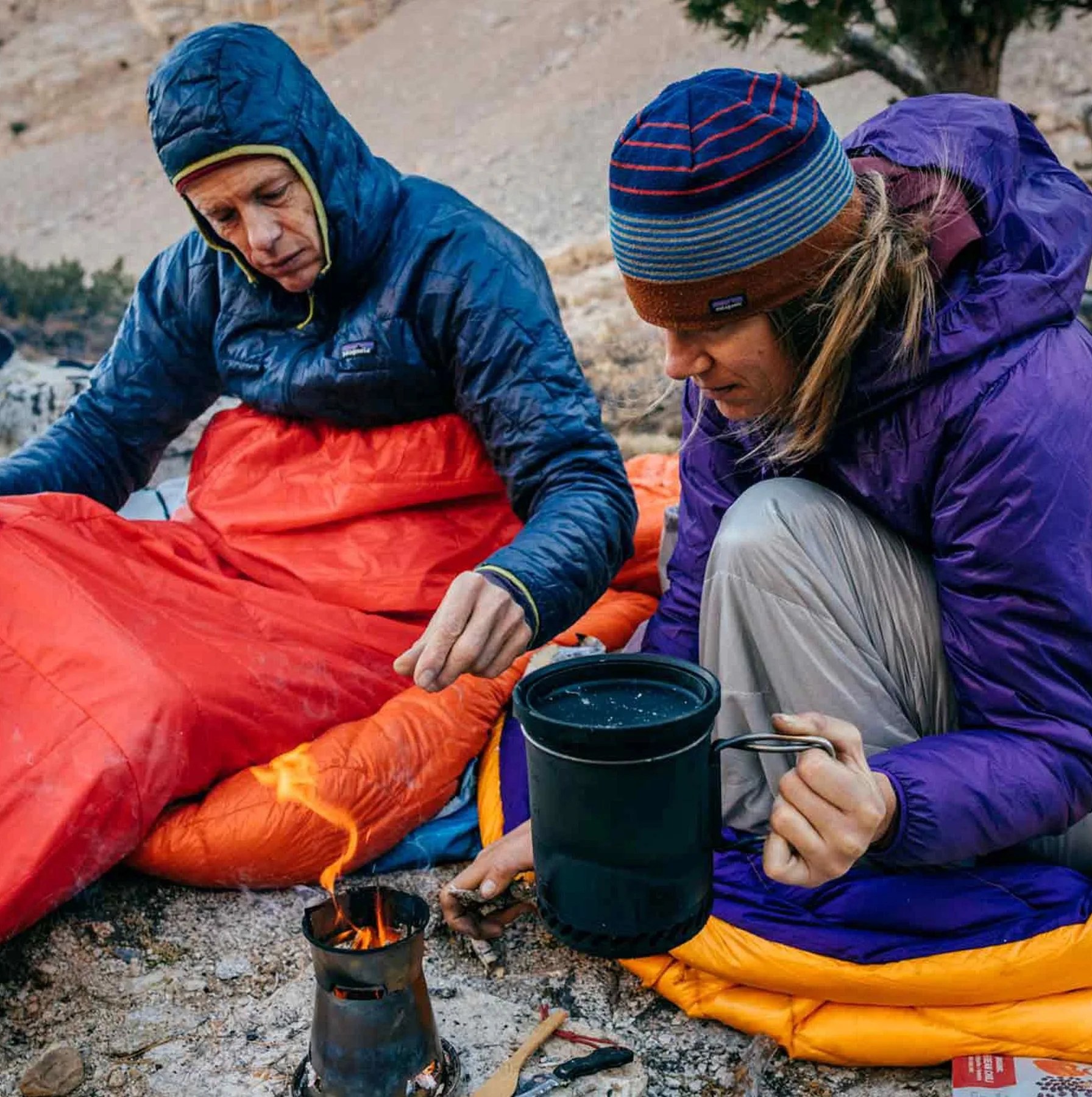 two people cooking over a camping stove