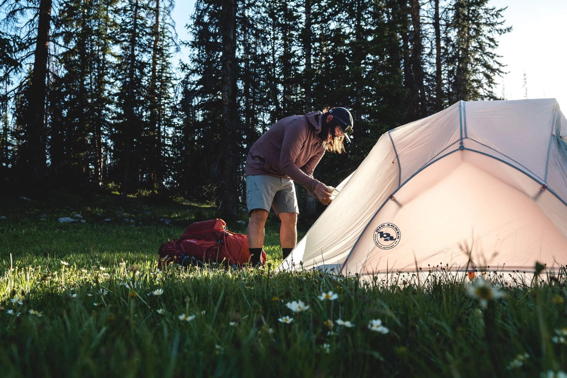 man setting up tent by forest
